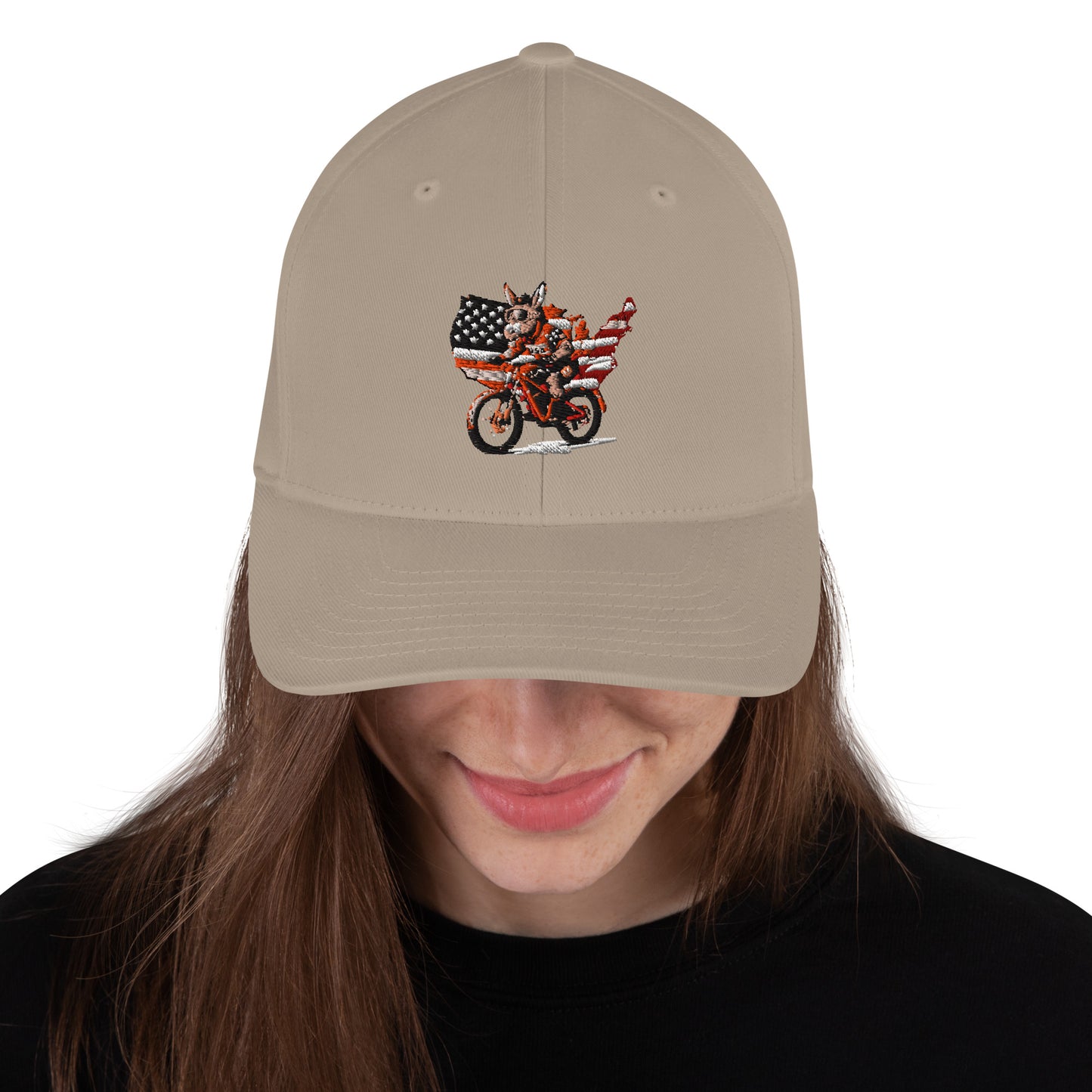 Beige cap with a graphic design of a person on a motorcycle with an American flag, worn by a person with long brown hair.