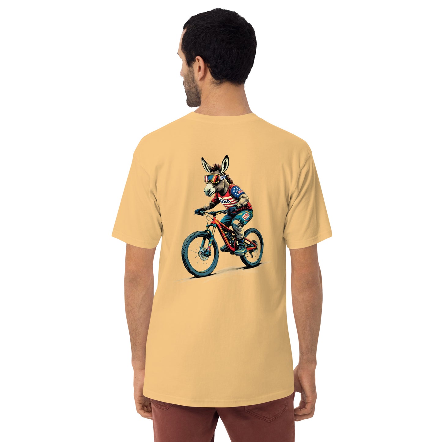 Man wearing a mustard yellow t-shirt with a colorful graphic of a donkey on a bicycle on the back.