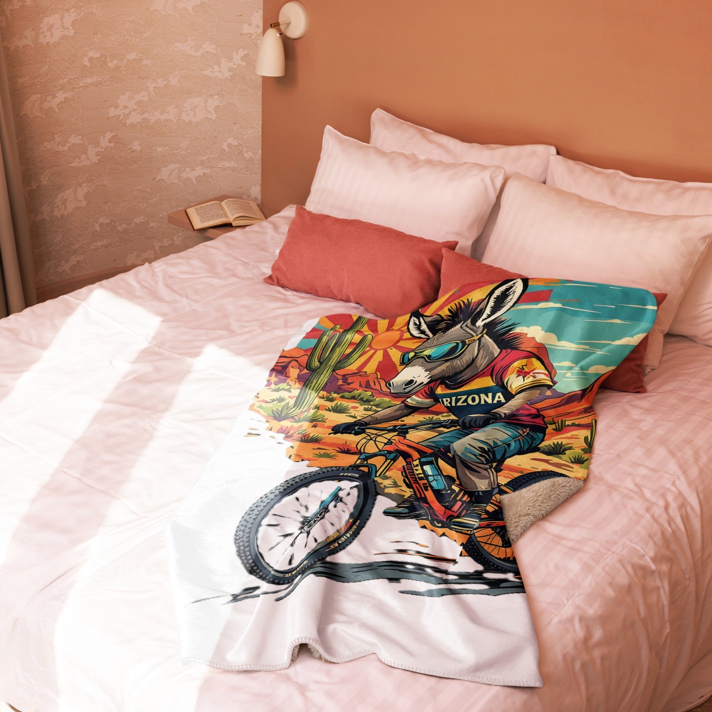 Colorful pillow with a donkey and bicycle design on a bed with pink bedding.