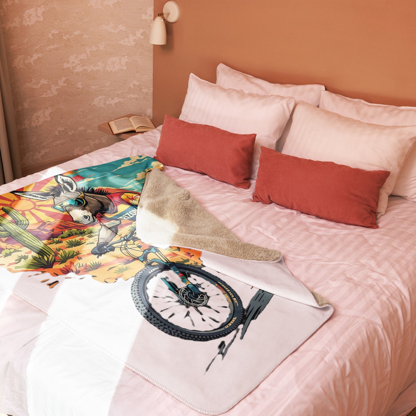 Bed with colorful blanket featuring a bicycle design and red pillows.