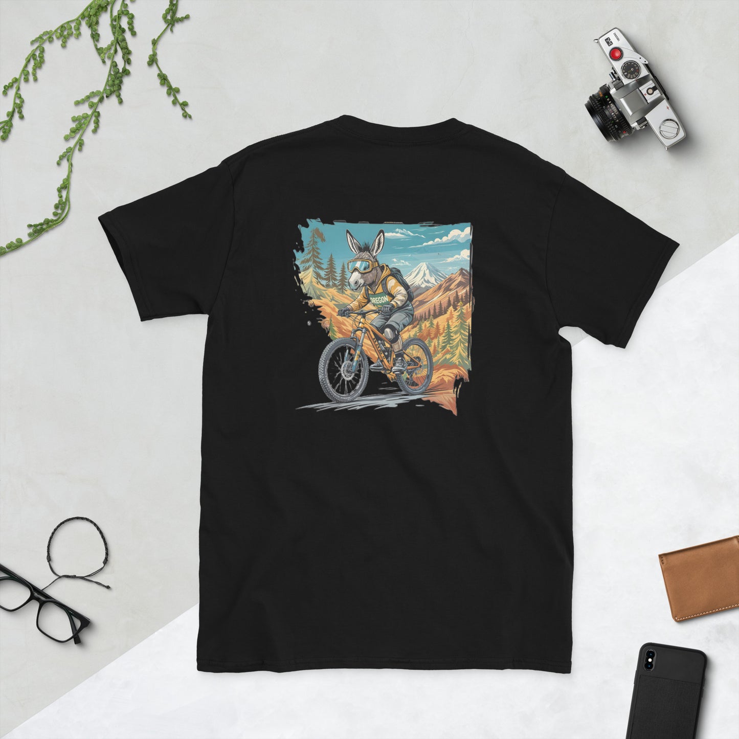 Black t-shirt with a graphic of a donkey riding a bike in a mountainous landscape on a light gray background.
