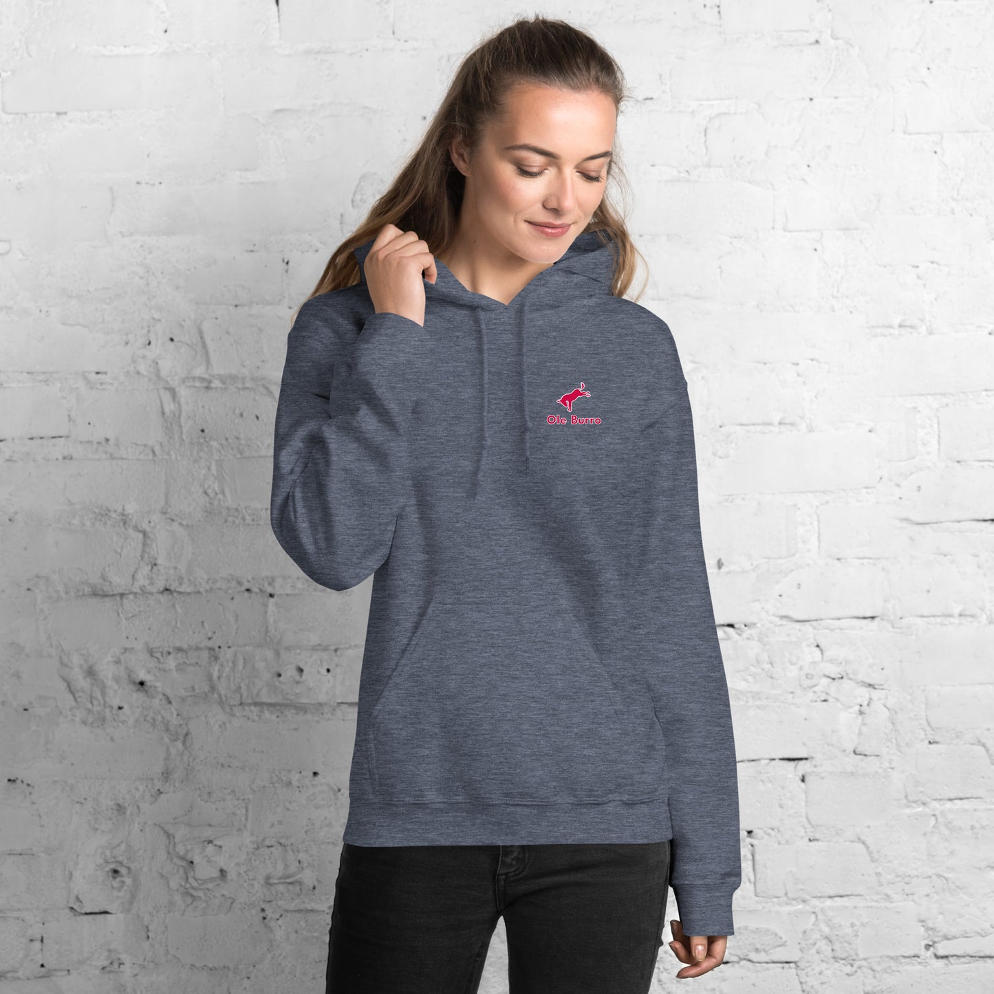 Woman wearing a gray hoodie with a logo against a white brick wall