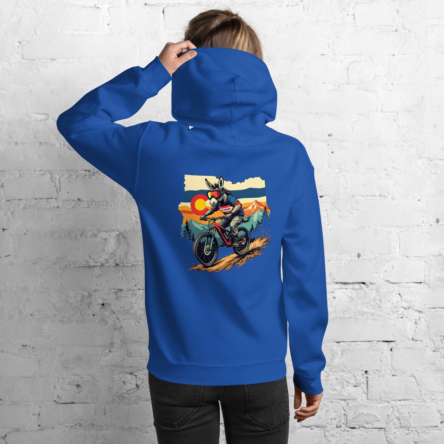 Person wearing a blue hoodie with a graphic of a person on a motorcycle against a mountainous background.