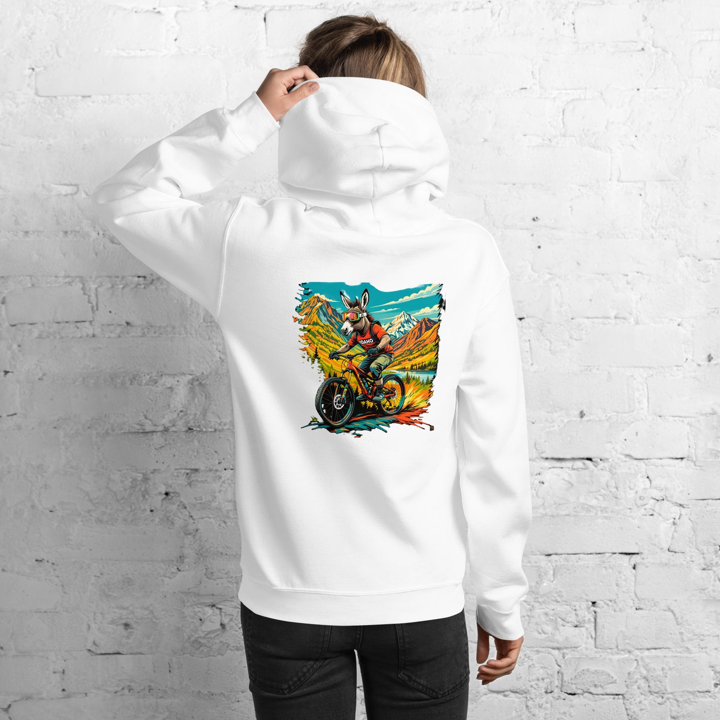 Person wearing a white hoodie with a colorful graphic on the back against a white brick wall.