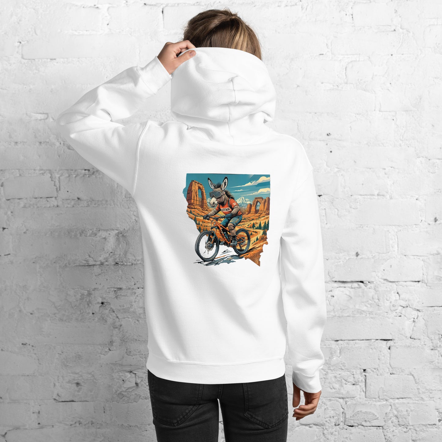 Person wearing a white hoodie with a colorful graphic on the back against a white brick wall.