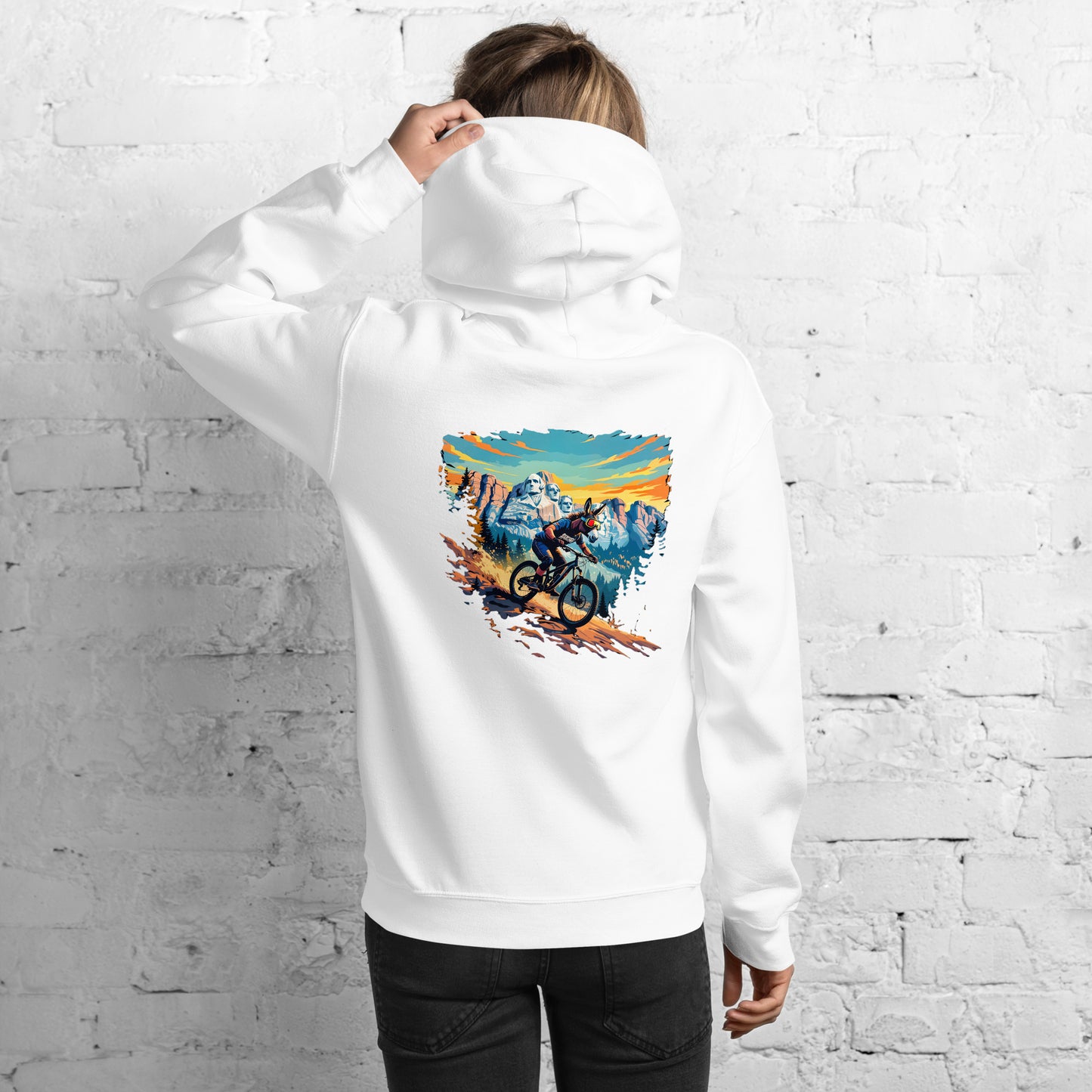 Person wearing a white hoodie with a colorful graphic on the back against a white brick wall.