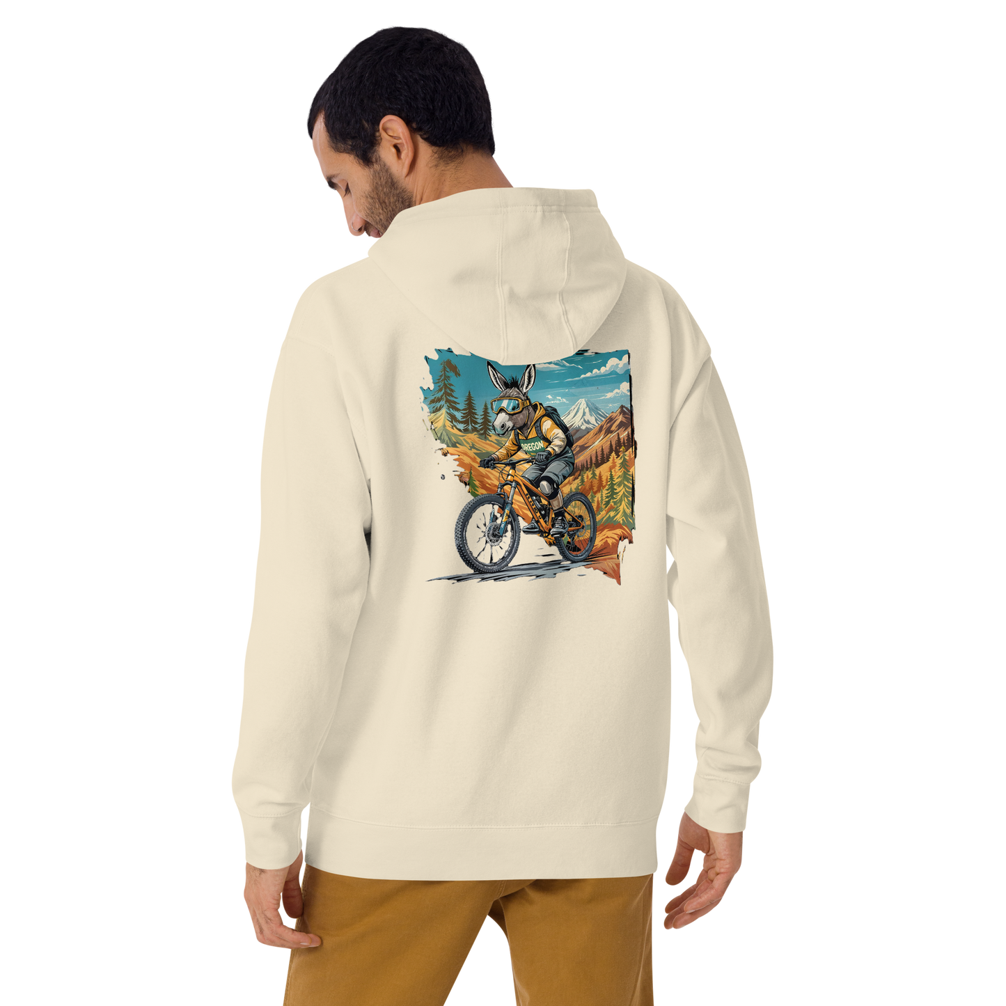 Person wearing a cream hoodie with a graphic of a person on a motorcycle in nature on the back.