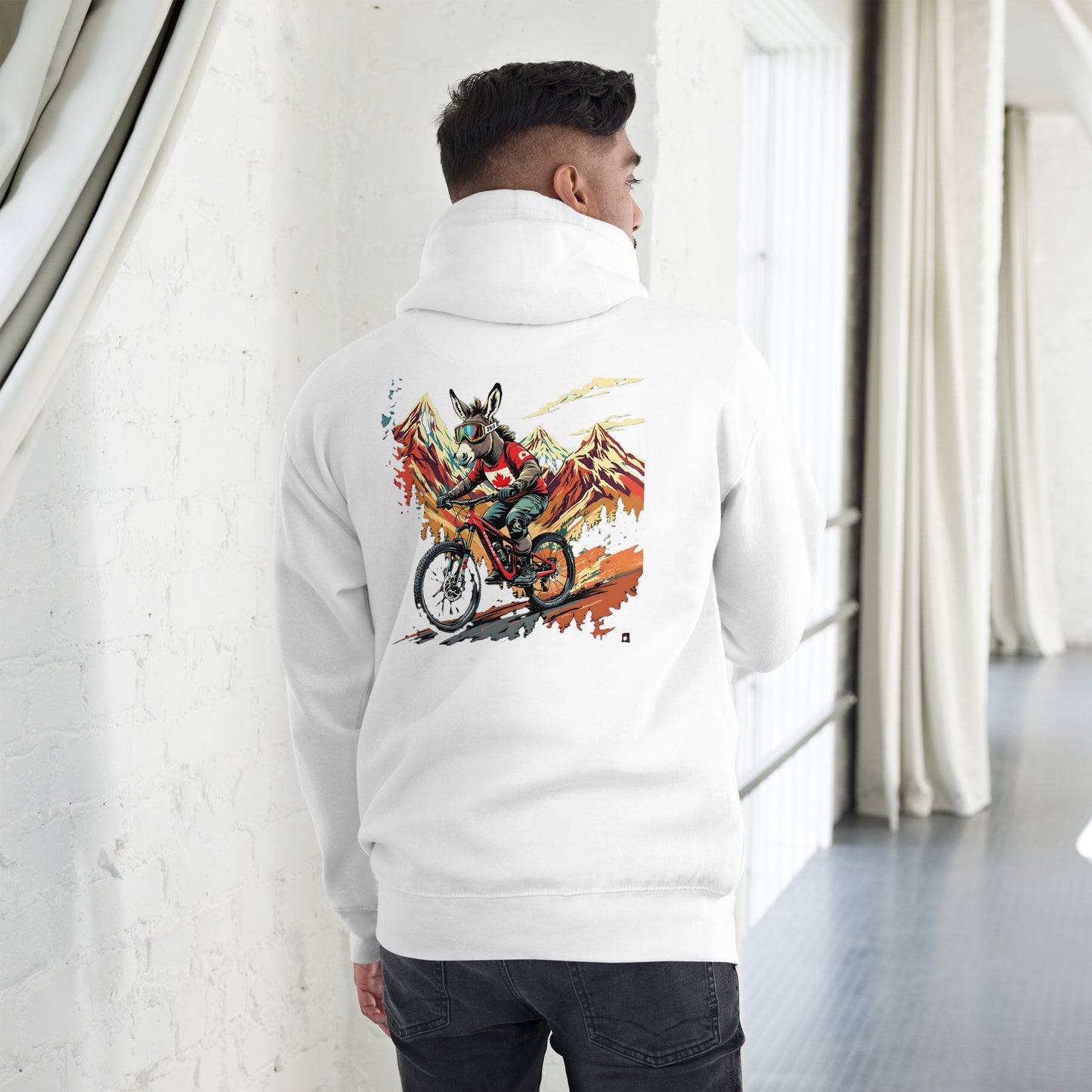 Person wearing a white hoodie with a colorful graphic on the back, standing in a minimalistic room.