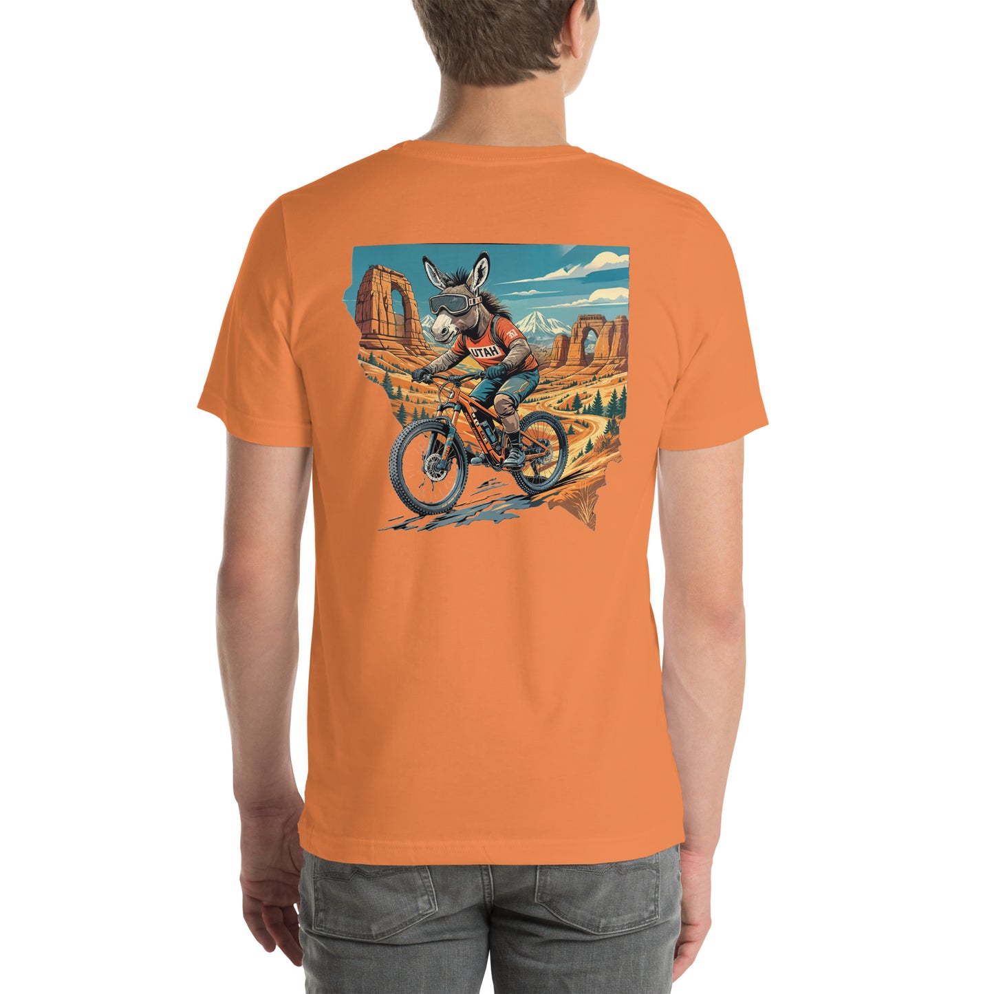 Person wearing an orange t-shirt with a graphic of a donkey riding a bike in a desert landscape.