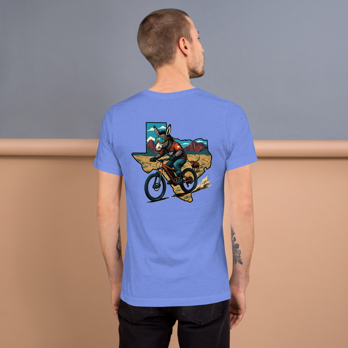 Man wearing a blue t-shirt with a graphic design on the back, standing against a gradient background.