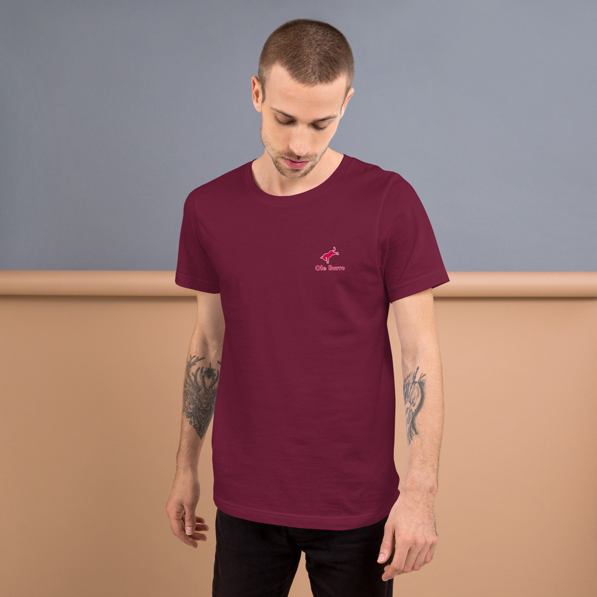 Man wearing a maroon t-shirt with a small logo on a plain background