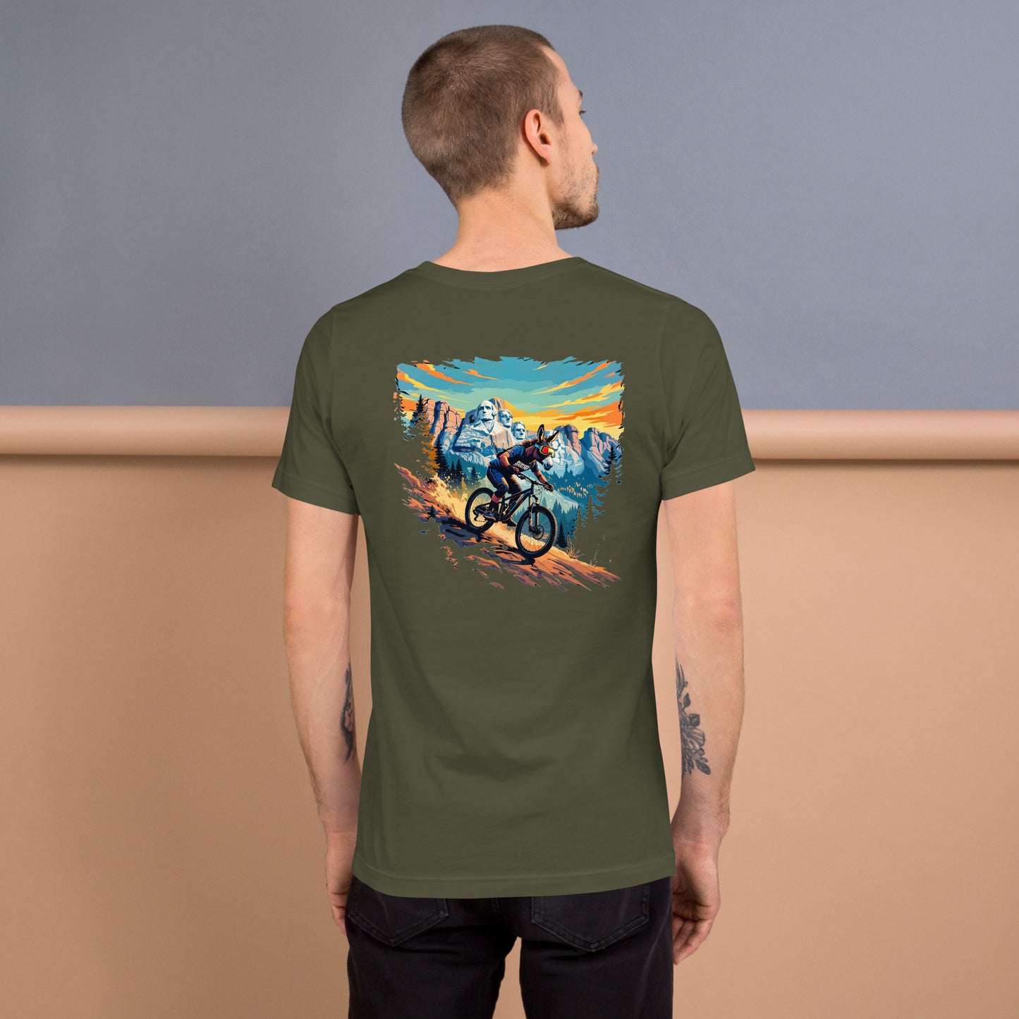 Person wearing a green t-shirt with a mountain bike graphic on the back, standing against a plain background.