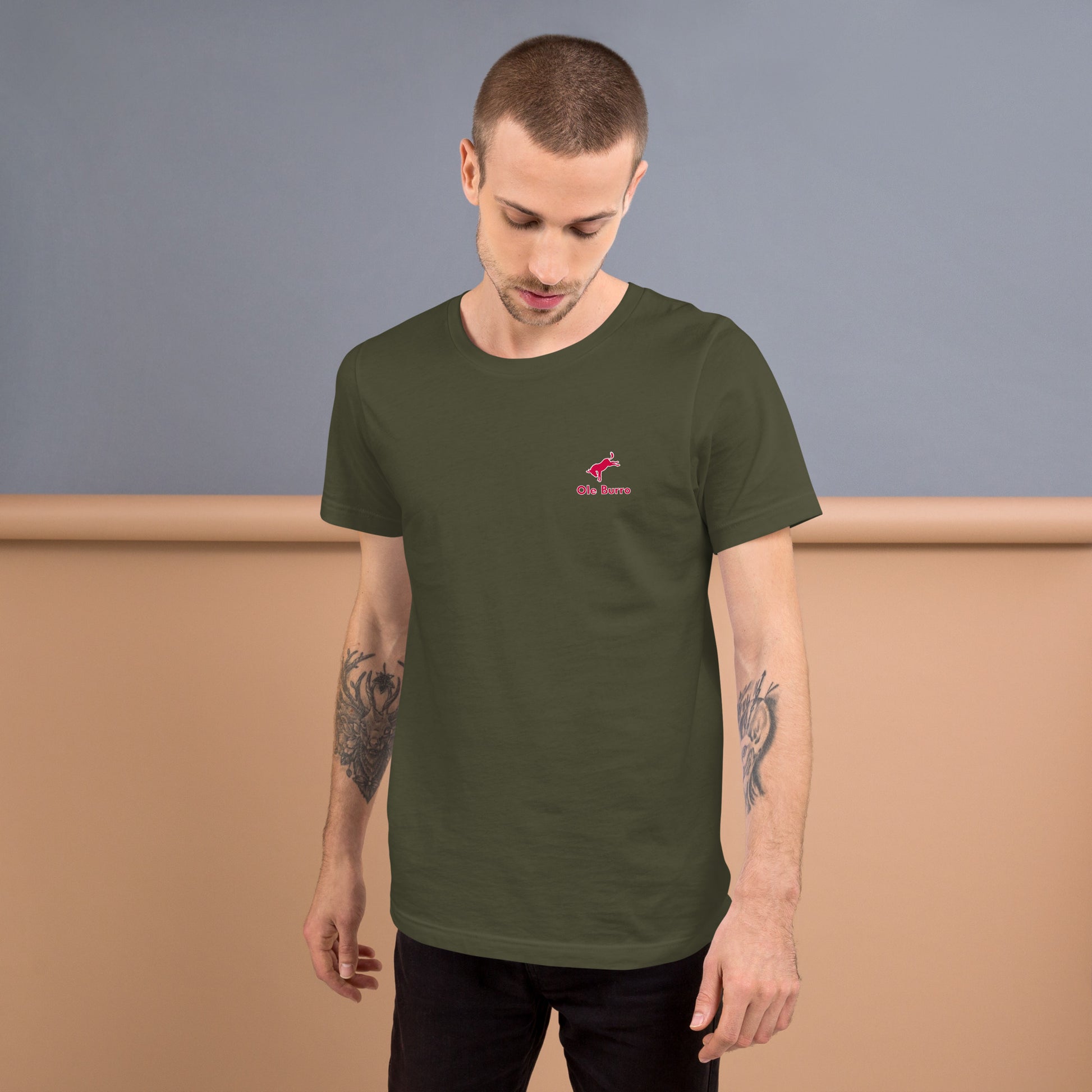 Man wearing a green t-shirt with a small red logo on a plain background
