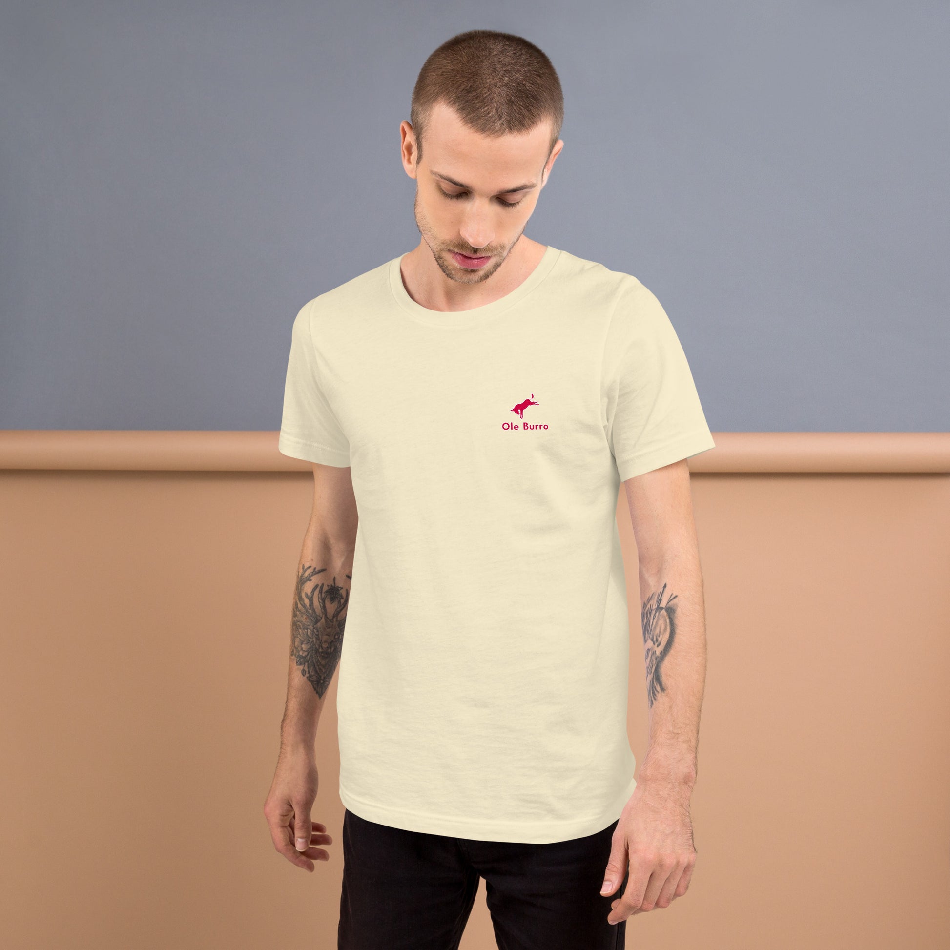 Man wearing a light-colored t-shirt with a small logo on a plain background