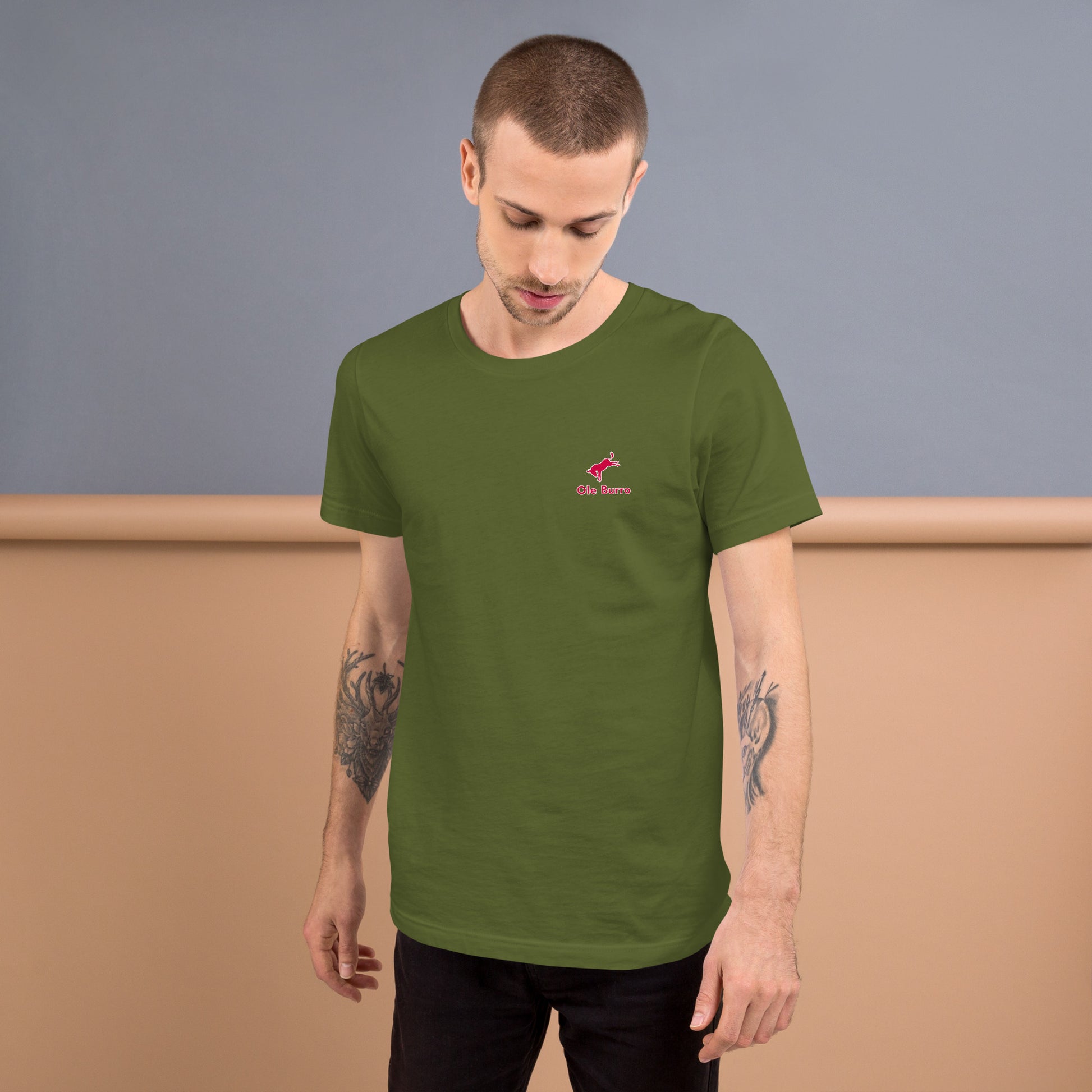 Man wearing a green t-shirt with a small logo on a plain background
