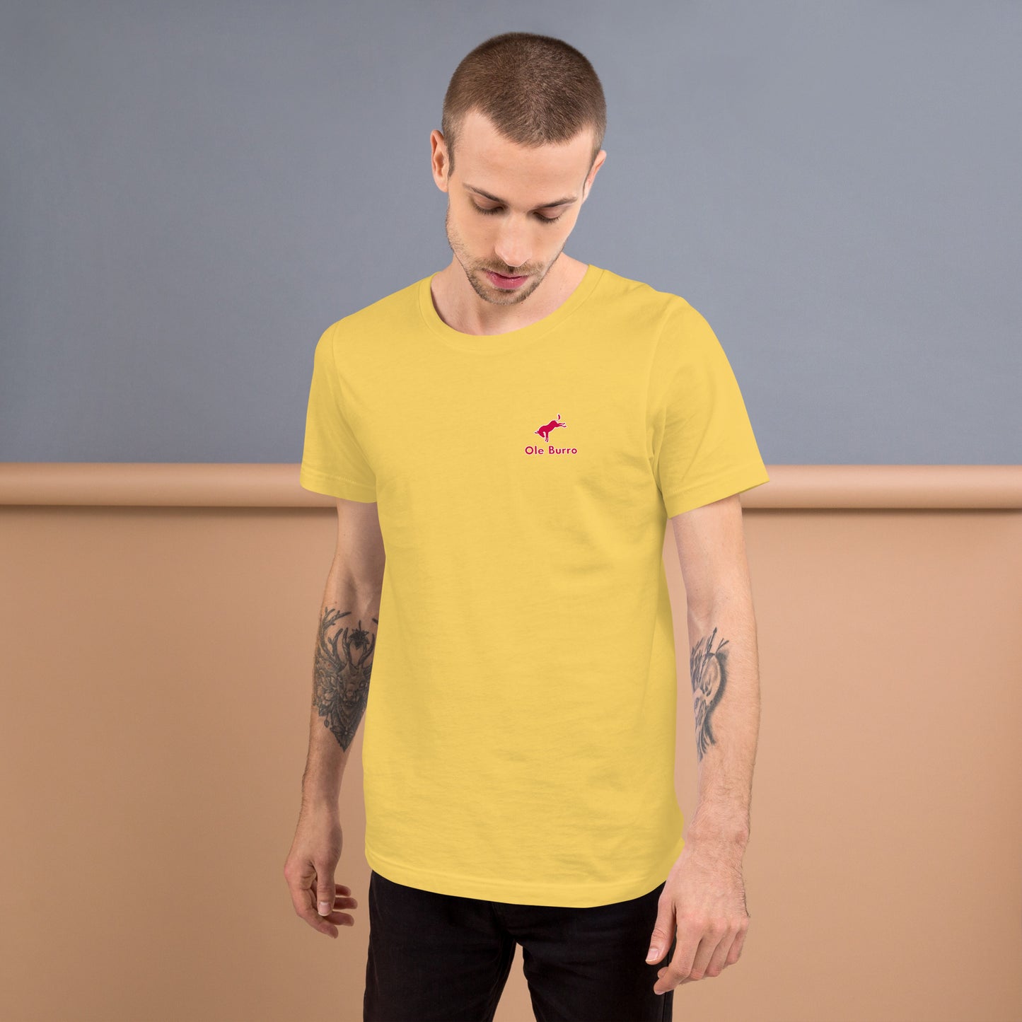 Man wearing a yellow t-shirt with a small logo on a plain background