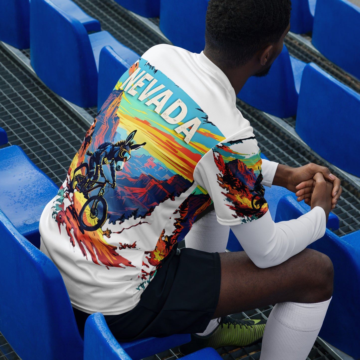 Person wearing a colorful hoodie with 'NEVADA' text sitting in blue stadium seats.