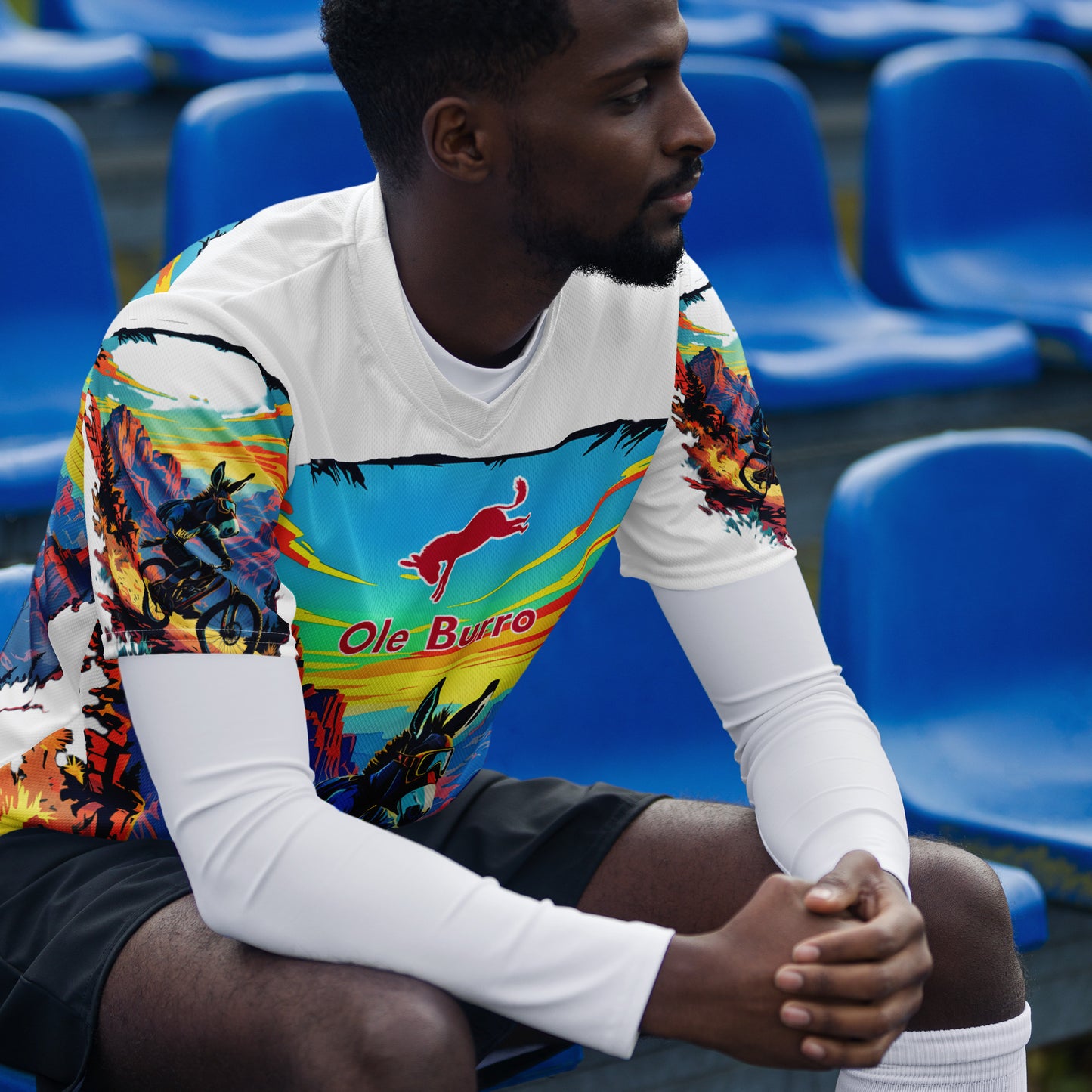Person wearing a colorful sports jersey with 'Ole Burro' branding sitting in blue stadium seats.