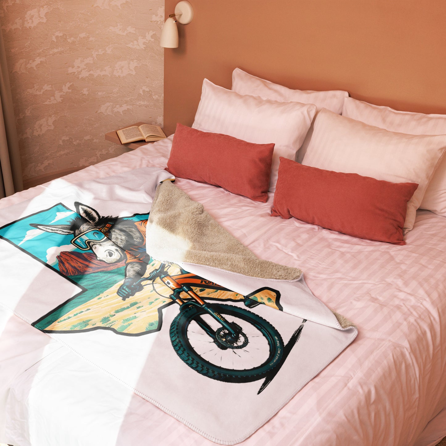 Bed with colorful blanket featuring a donkey and bicycle design, surrounded by pillows.