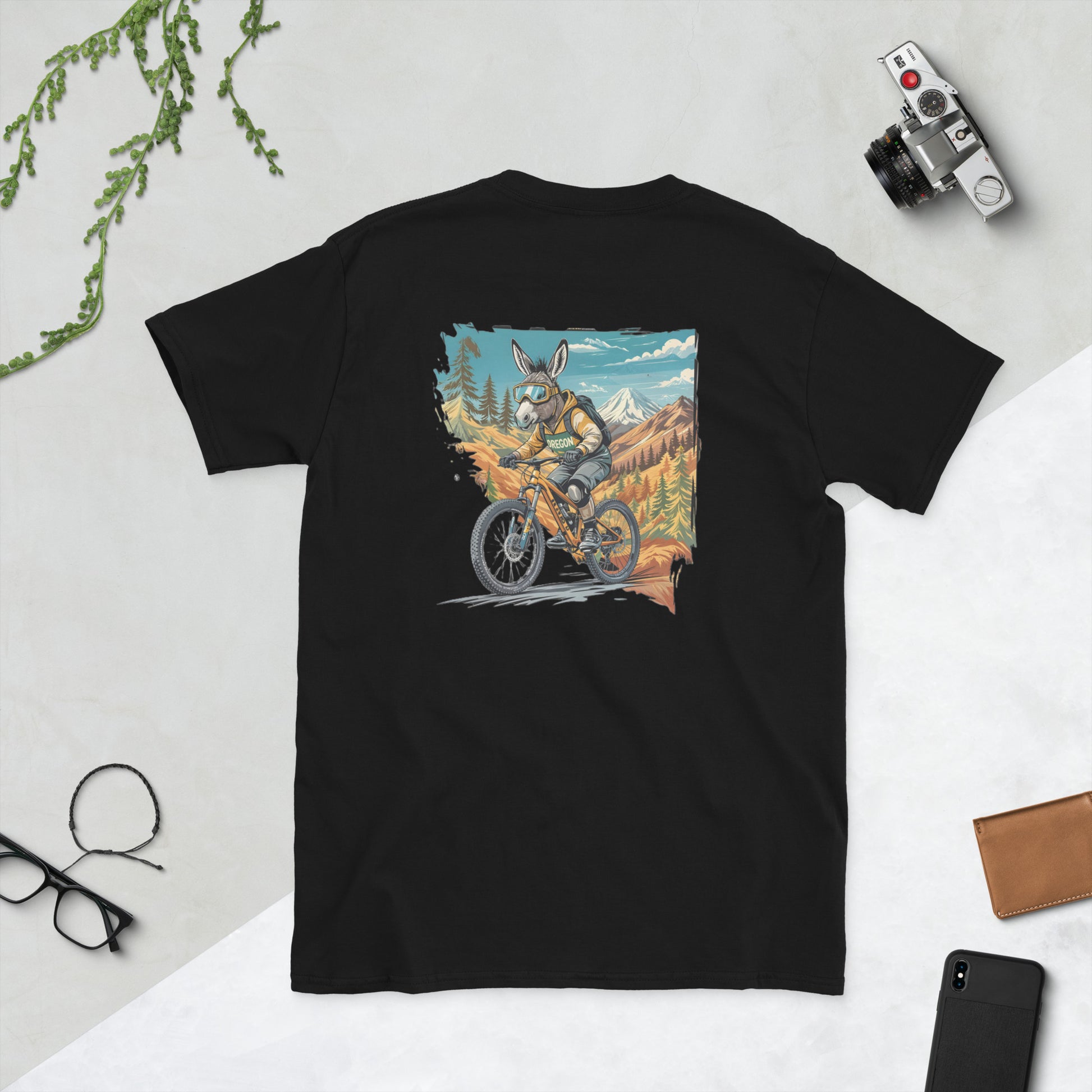 Black t-shirt with a graphic of a donkey riding a bike in a mountainous landscape on a light gray background.