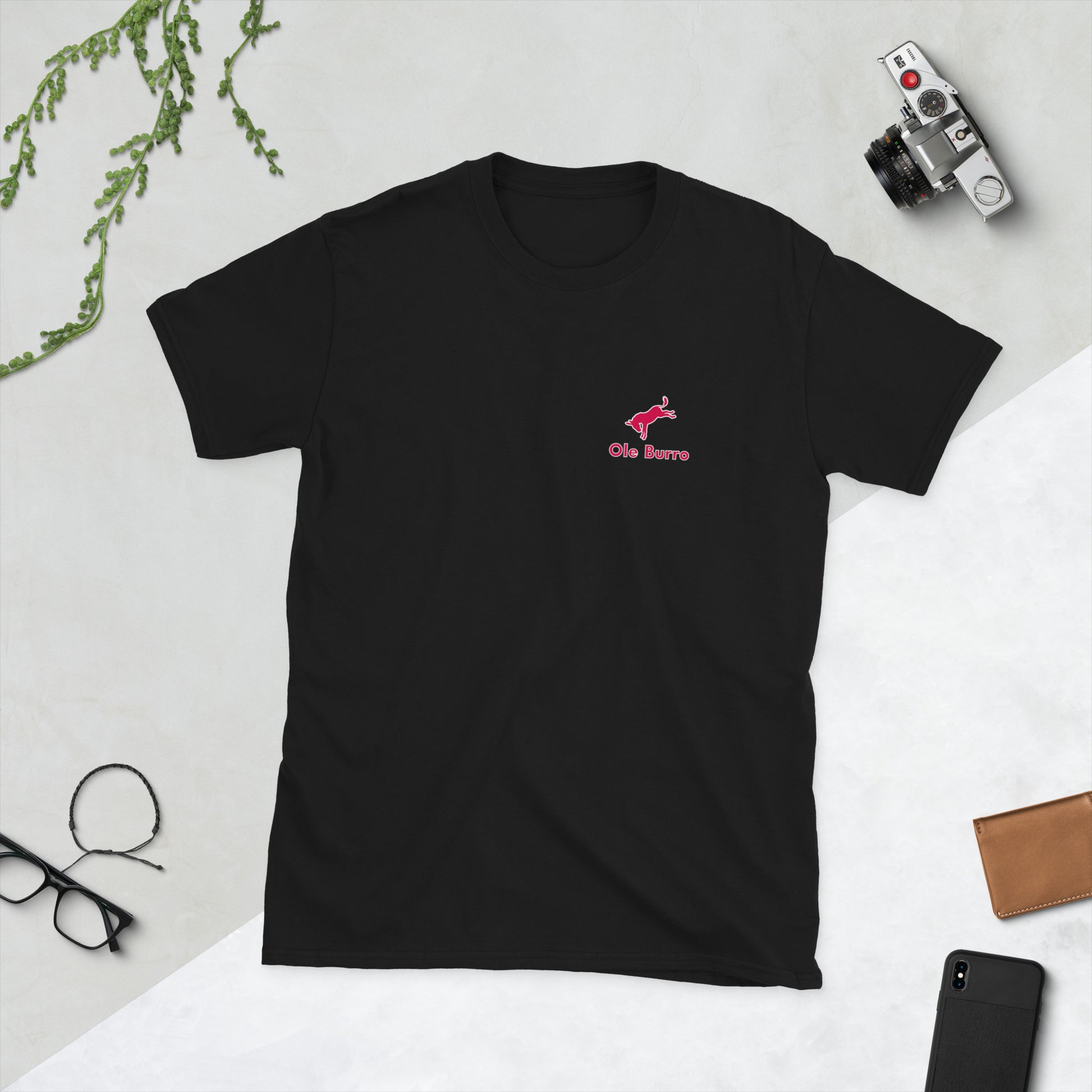 Black t-shirt with a red logo on a light gray surface with accessories around