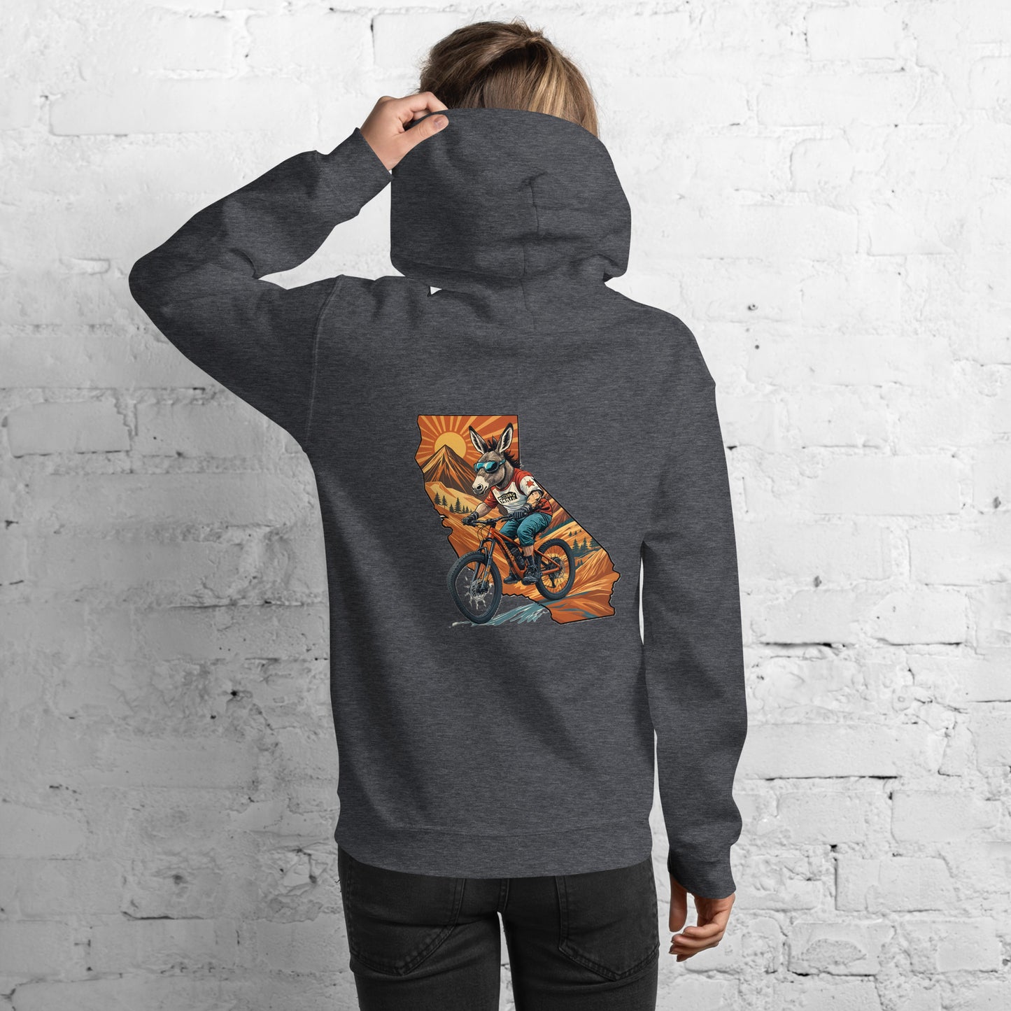 Person wearing a dark gray hoodie with a colorful graphic on the back against a white brick wall.