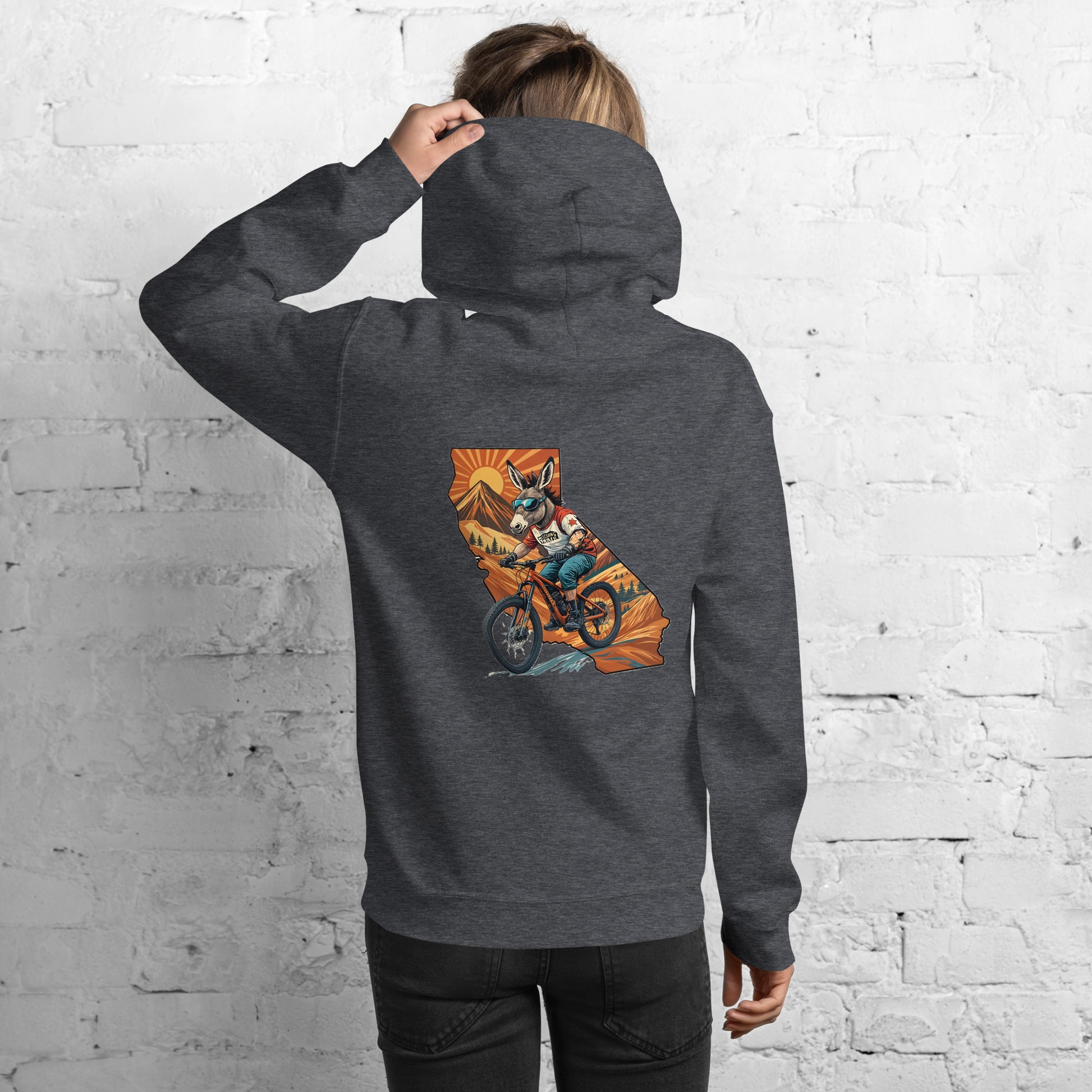 Person wearing a dark gray hoodie with a colorful graphic on the back against a white brick wall.