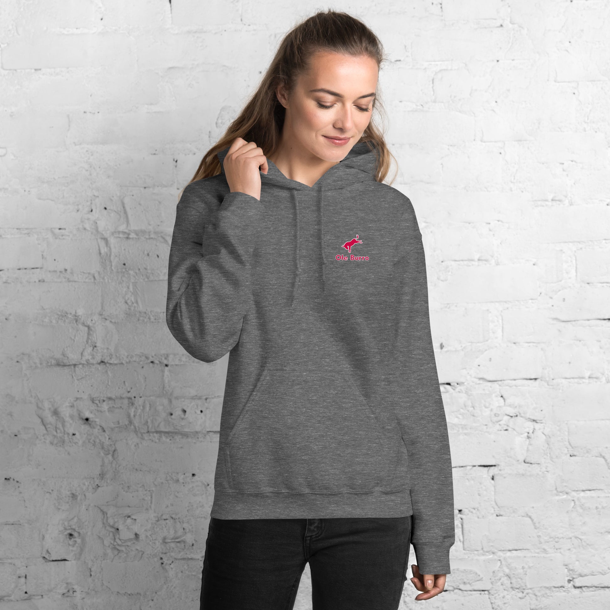 Woman wearing a gray hoodie with a logo against a white brick wall