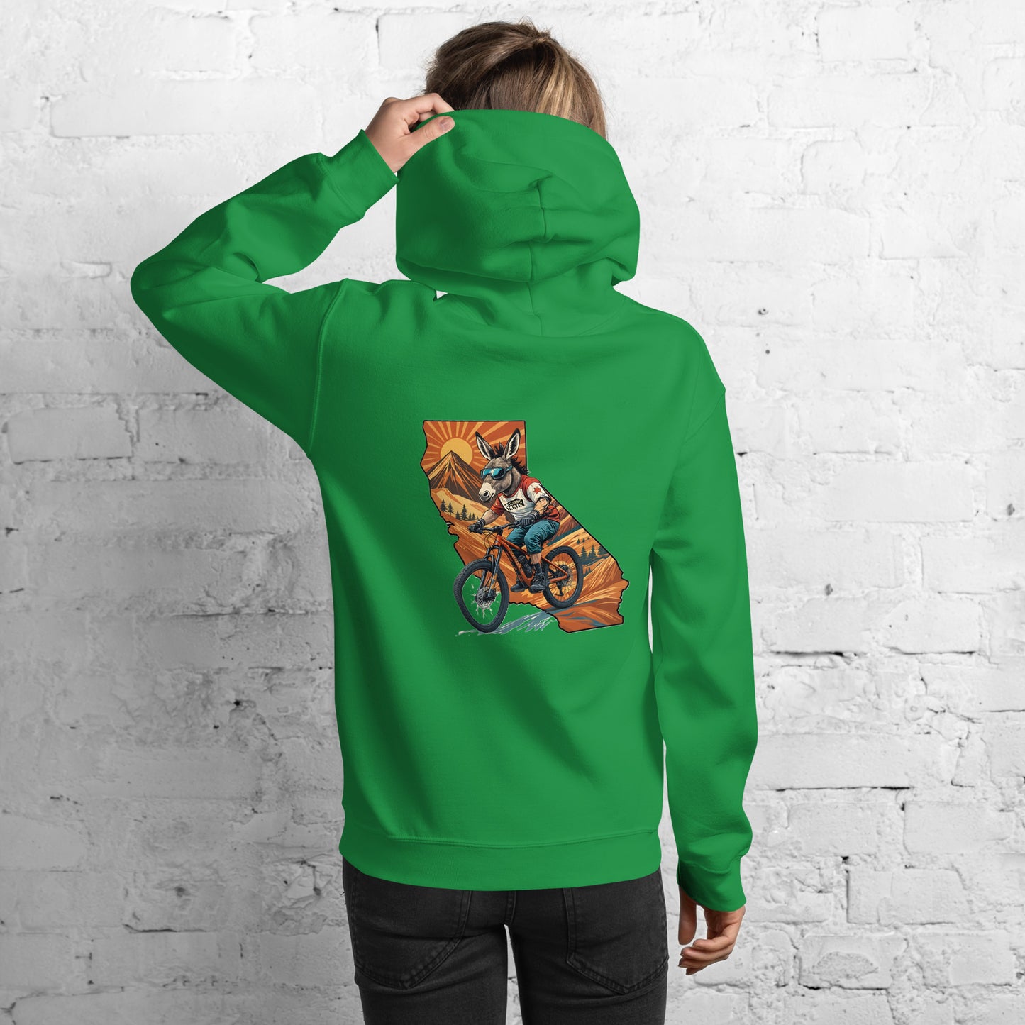 Person wearing a green hoodie with a graphic design on the back against a white brick wall.