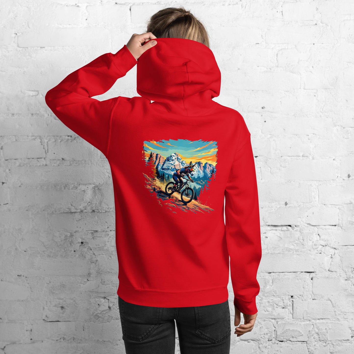 Person wearing a red hoodie with a mountain bike graphic on the back against a white brick wall.