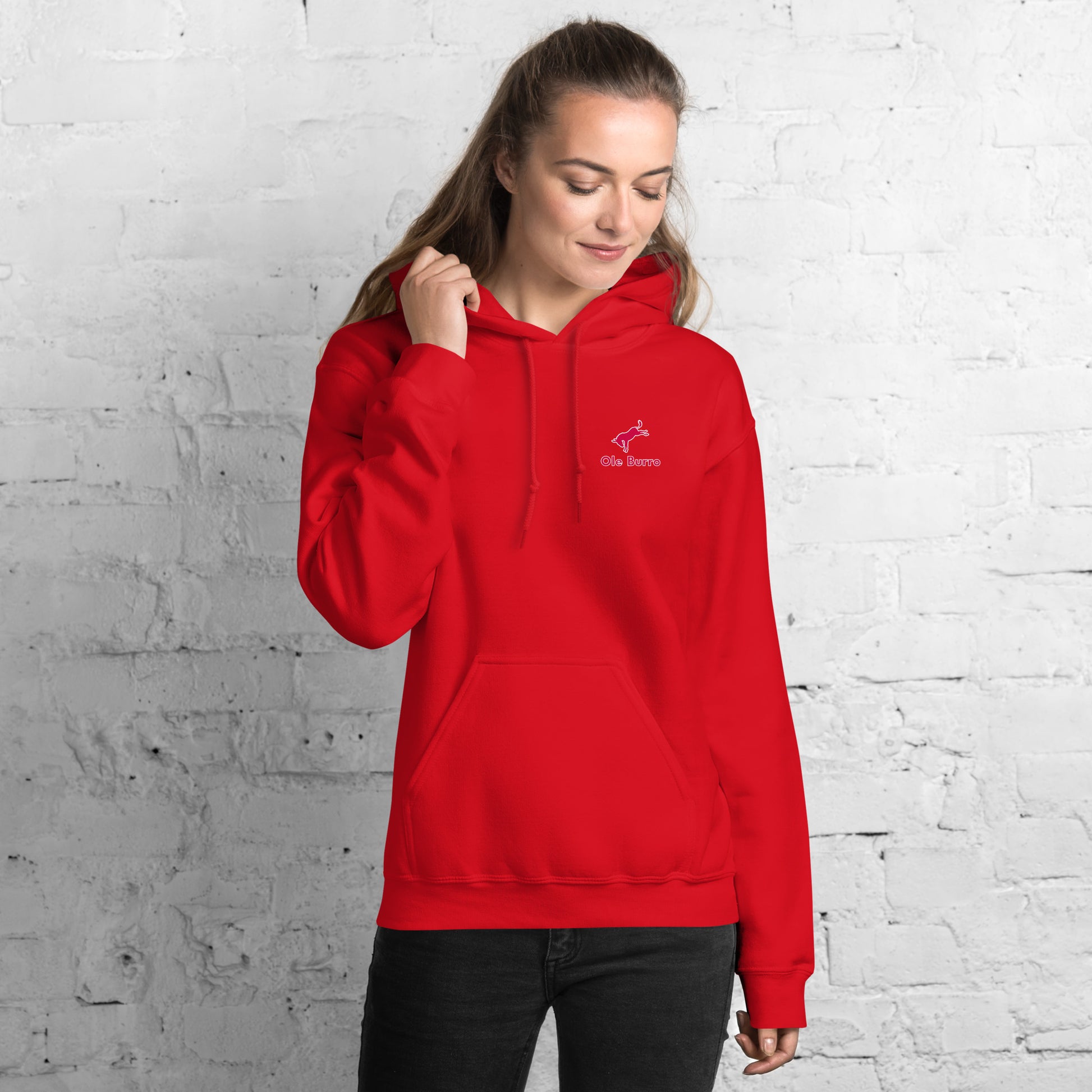 Person wearing a red hoodie with a logo against a white brick wall