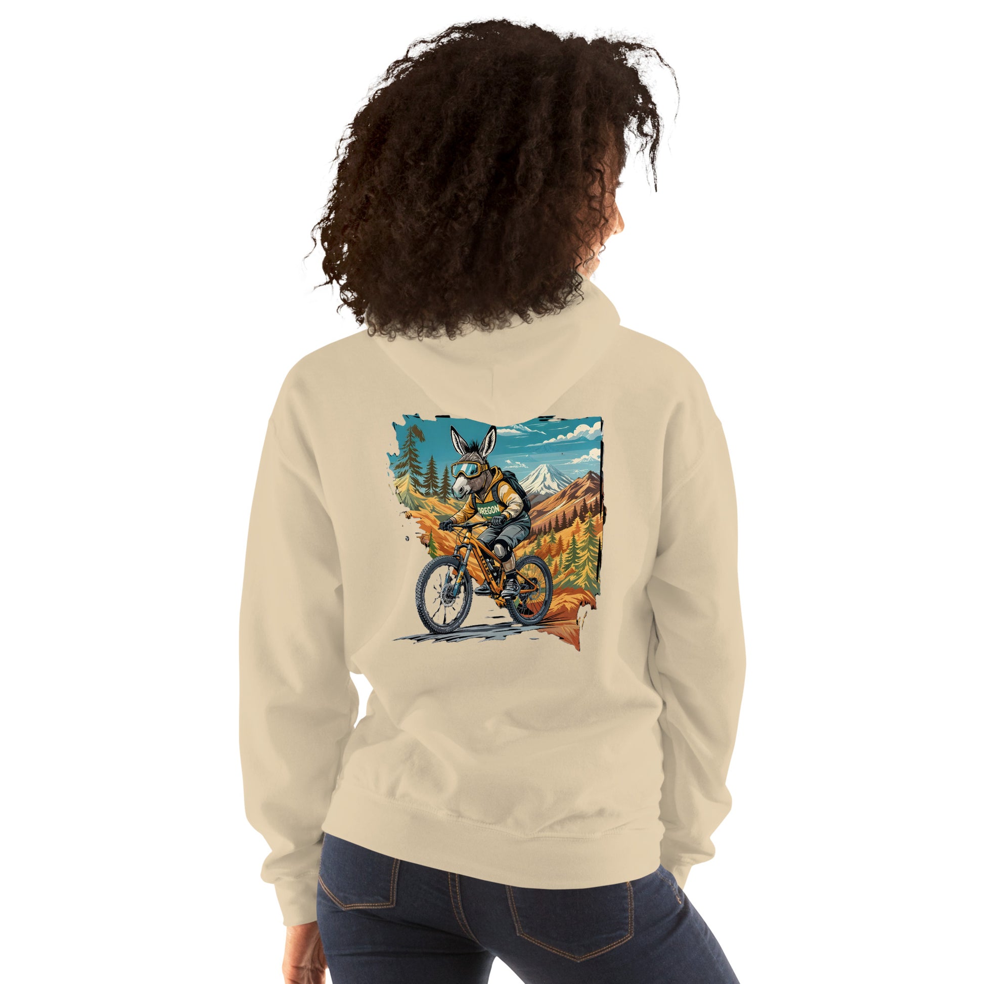 Person wearing a beige hoodie with a graphic of a person riding a bike in a mountainous landscape on the back.