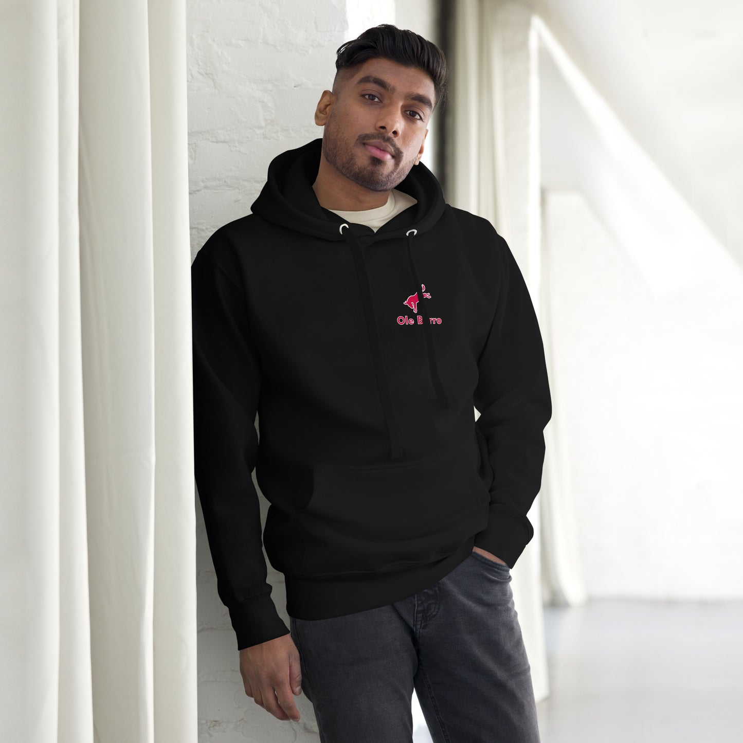 Man wearing a black hoodie with a pink logo in a minimalistic setting
