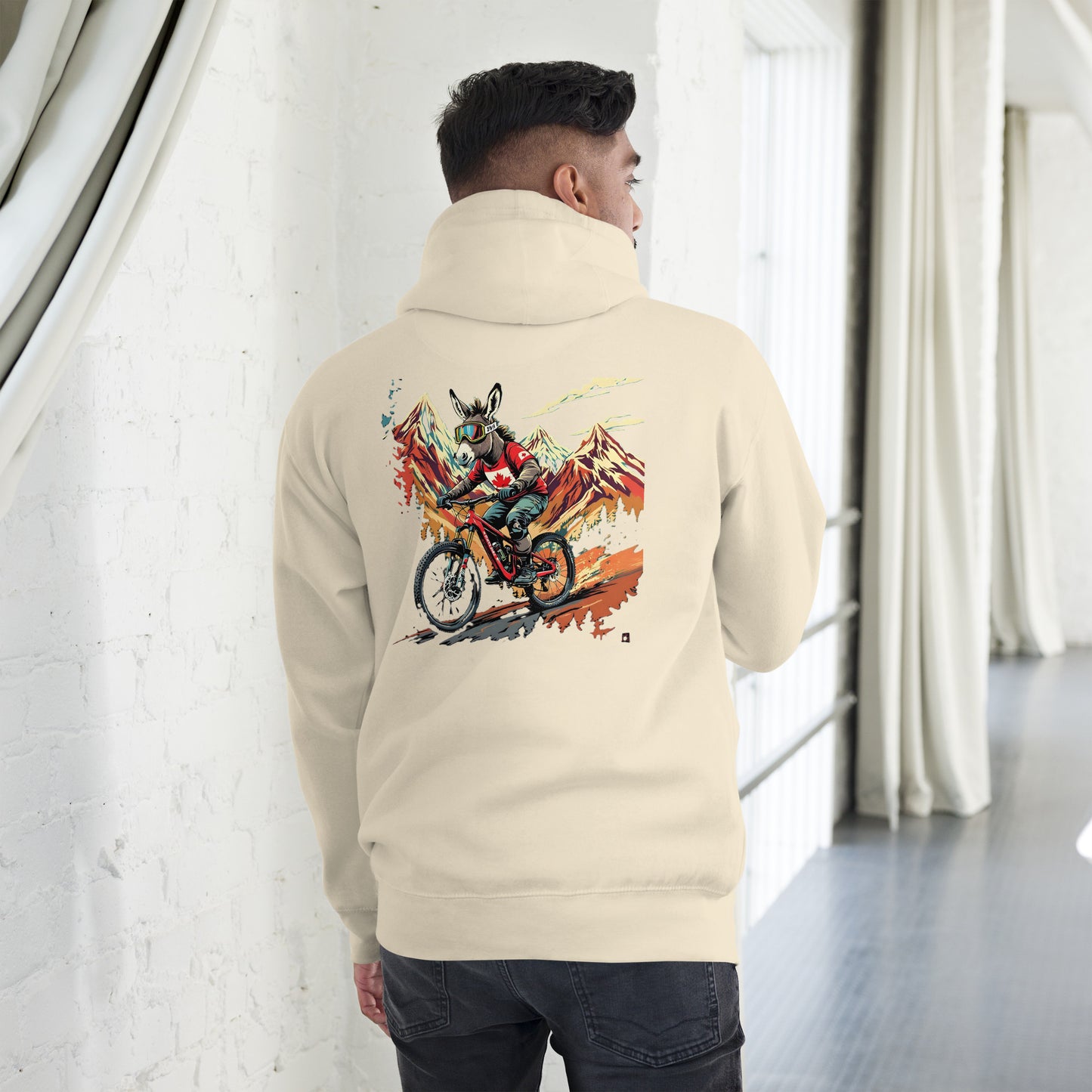 Person wearing a beige hoodie with a colorful motorcycle graphic on the back, standing in a modern indoor setting.
