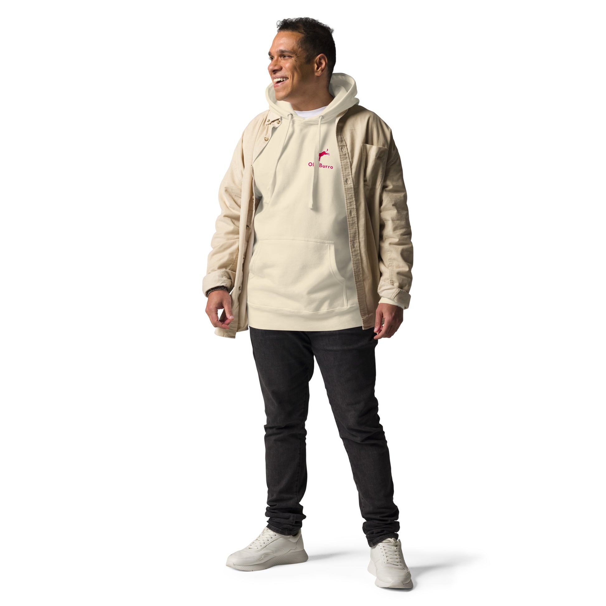 Man wearing a beige jacket over a white hoodie with a logo, dark pants, and white shoes on a white background