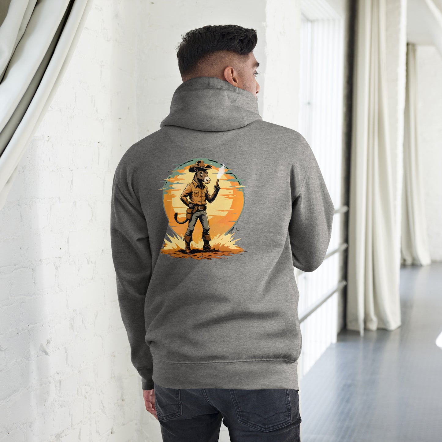 Person wearing a gray hoodie with a graphic design on the back, standing in a room with white walls and a window.