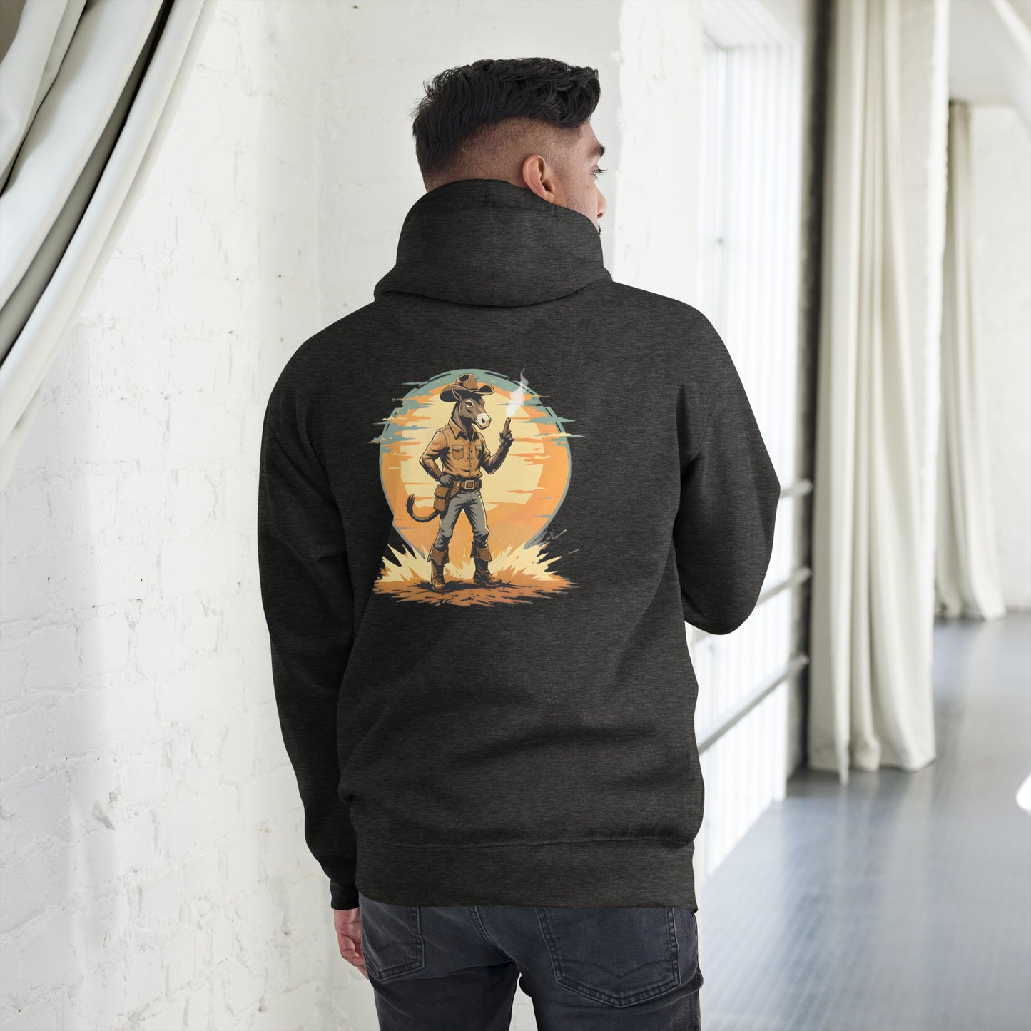 Person wearing a dark hoodie with a graphic design on the back, standing in a room with white walls and a gray floor.