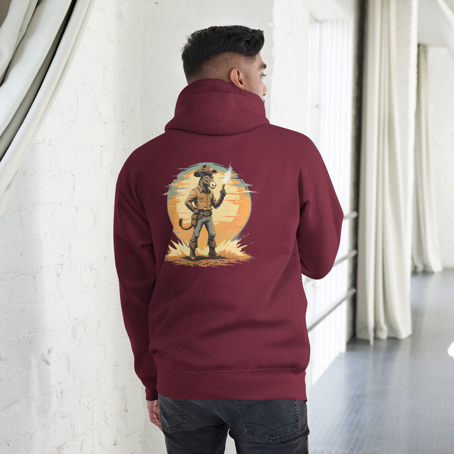 Person wearing a maroon hoodie with a graphic design on the back, standing in a room with white walls and curtains.