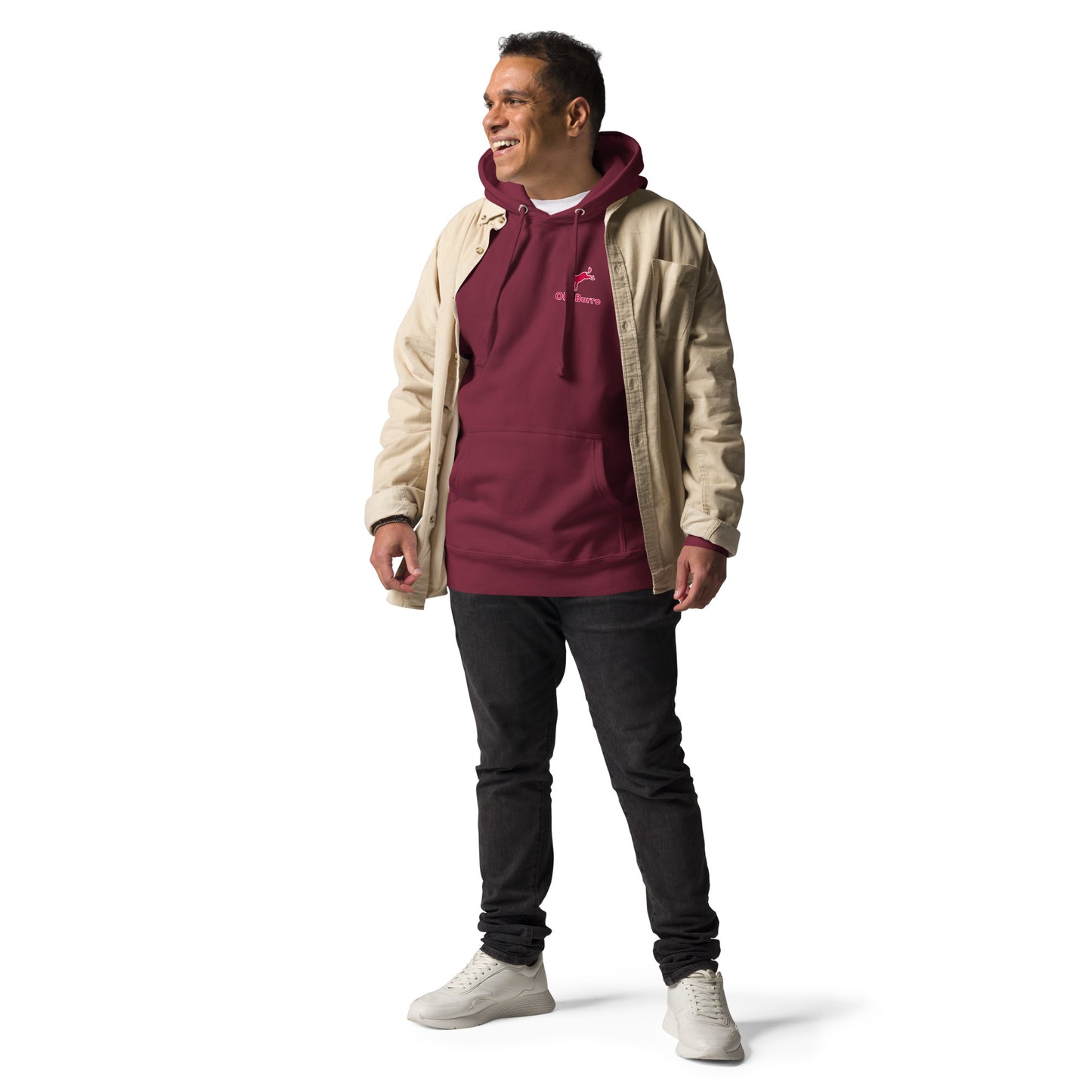 Man wearing a beige jacket over a maroon hoodie with a logo, black pants, and white shoes on a white background