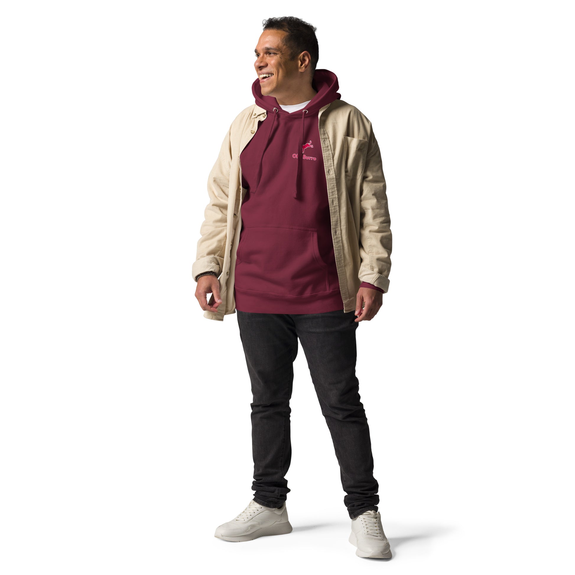 Man wearing a beige jacket over a maroon hoodie with a logo, black pants, and white shoes on a white background