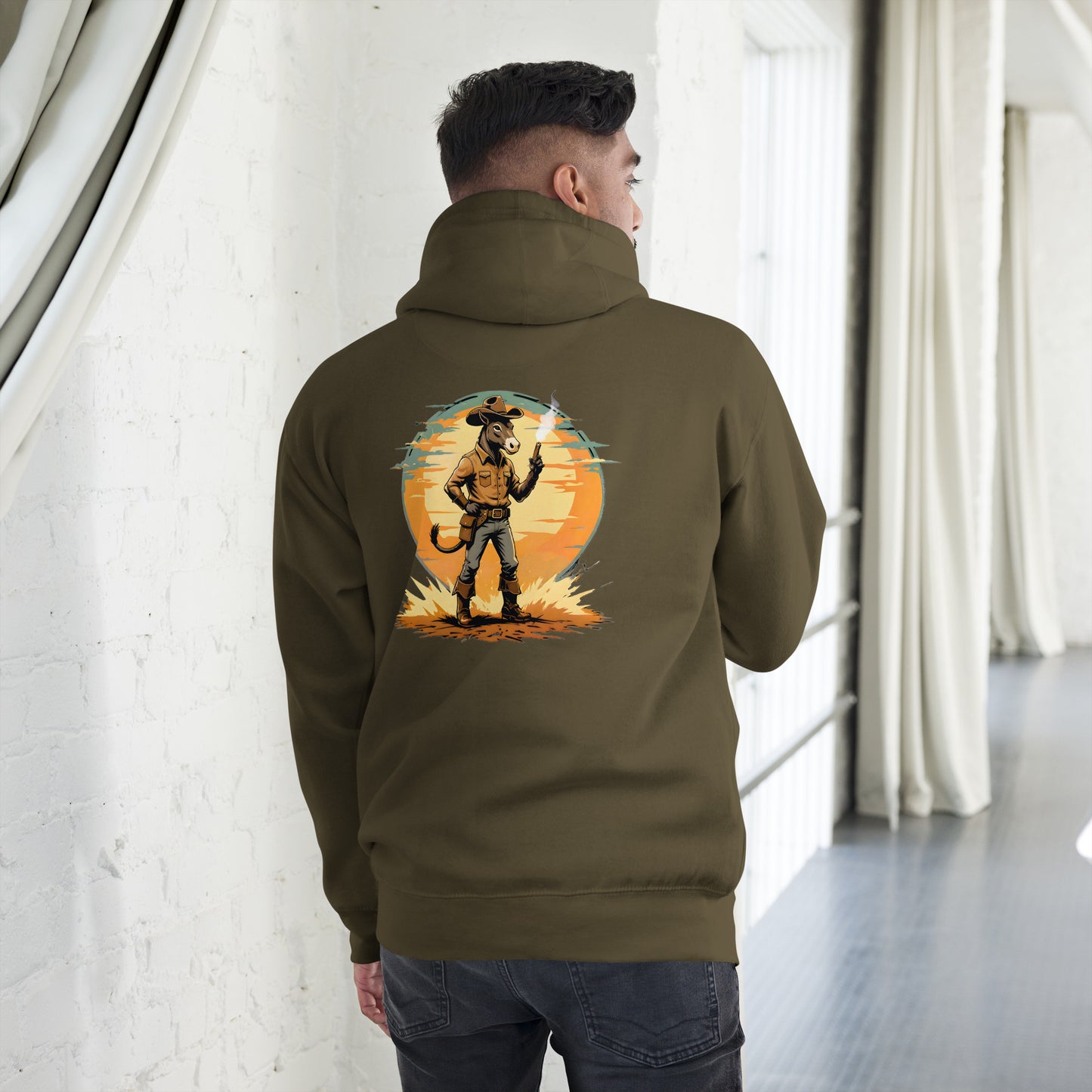 Person wearing a green hoodie with a graphic design on the back, standing in a room with white walls and a gray floor.