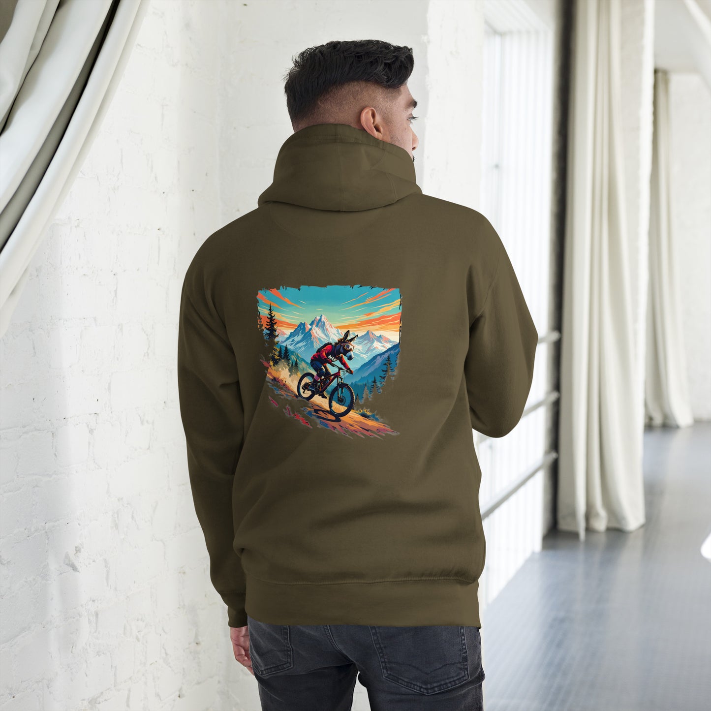 Person wearing a hoodie with a mountain bike graphic on the back in a room with white walls and large windows.