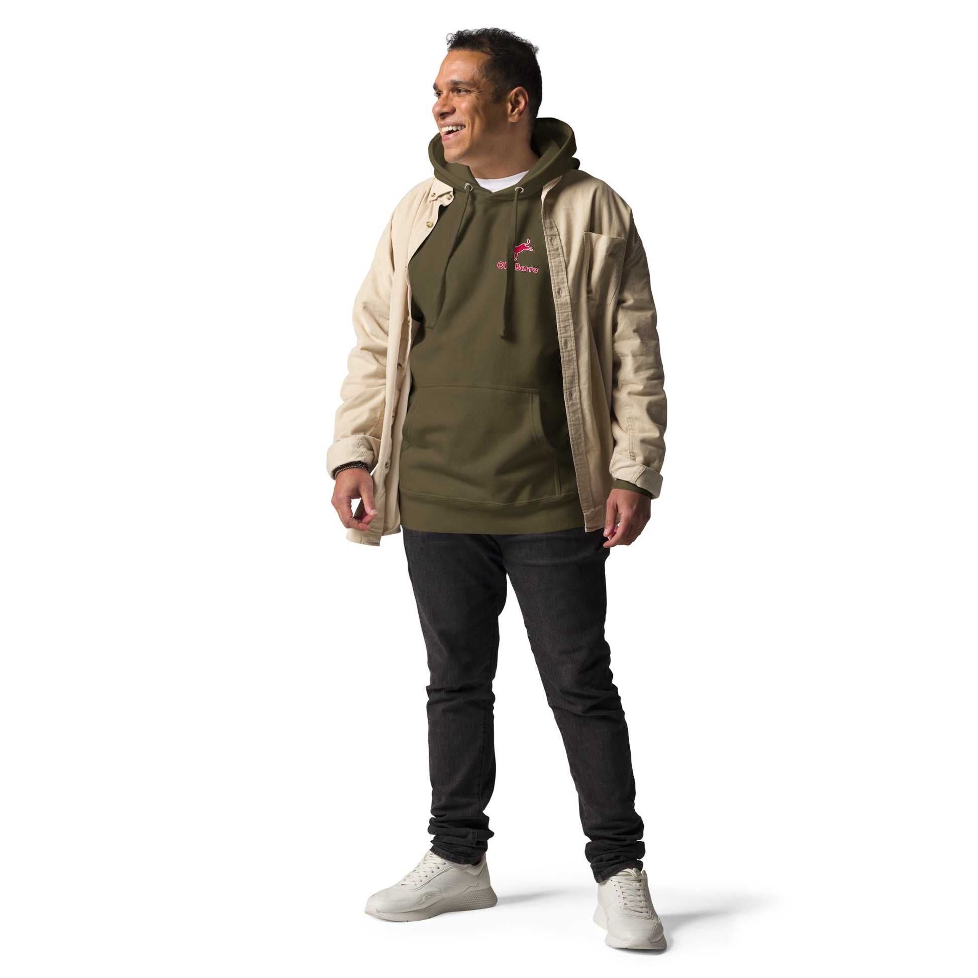 Man wearing a beige jacket over a green hoodie with a logo, standing against a white background