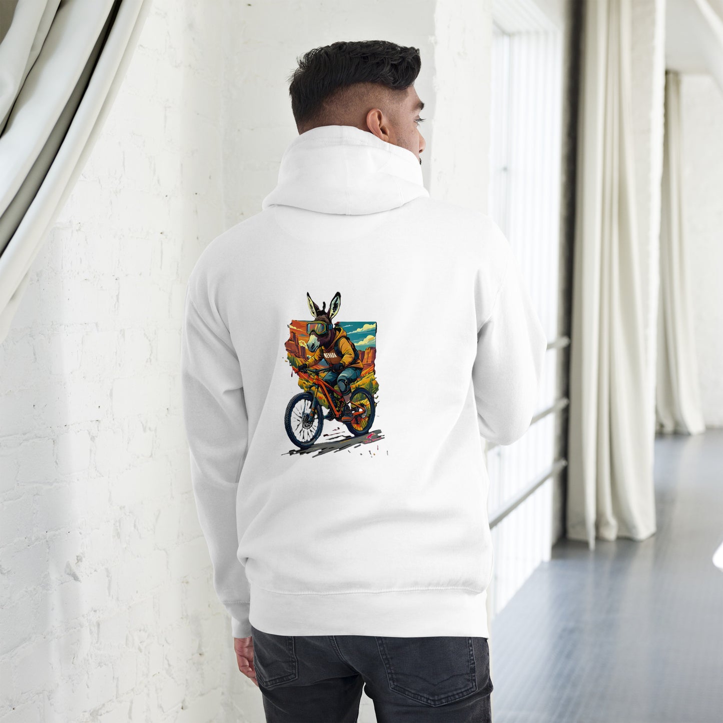 Person wearing a white hoodie with a colorful graphic on the back, standing in a minimalistic room.
