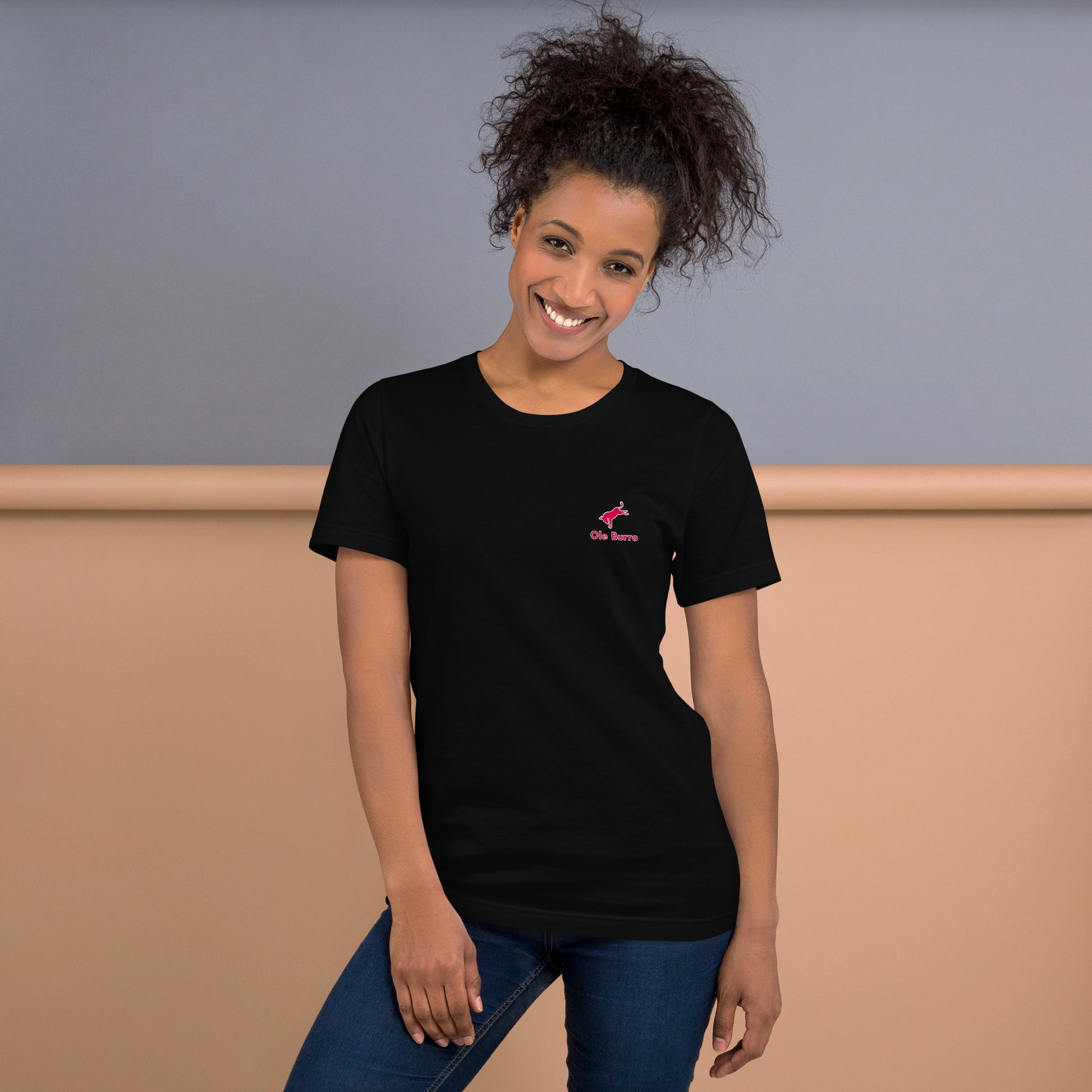 Woman wearing a black t-shirt with a small logo on a plain background