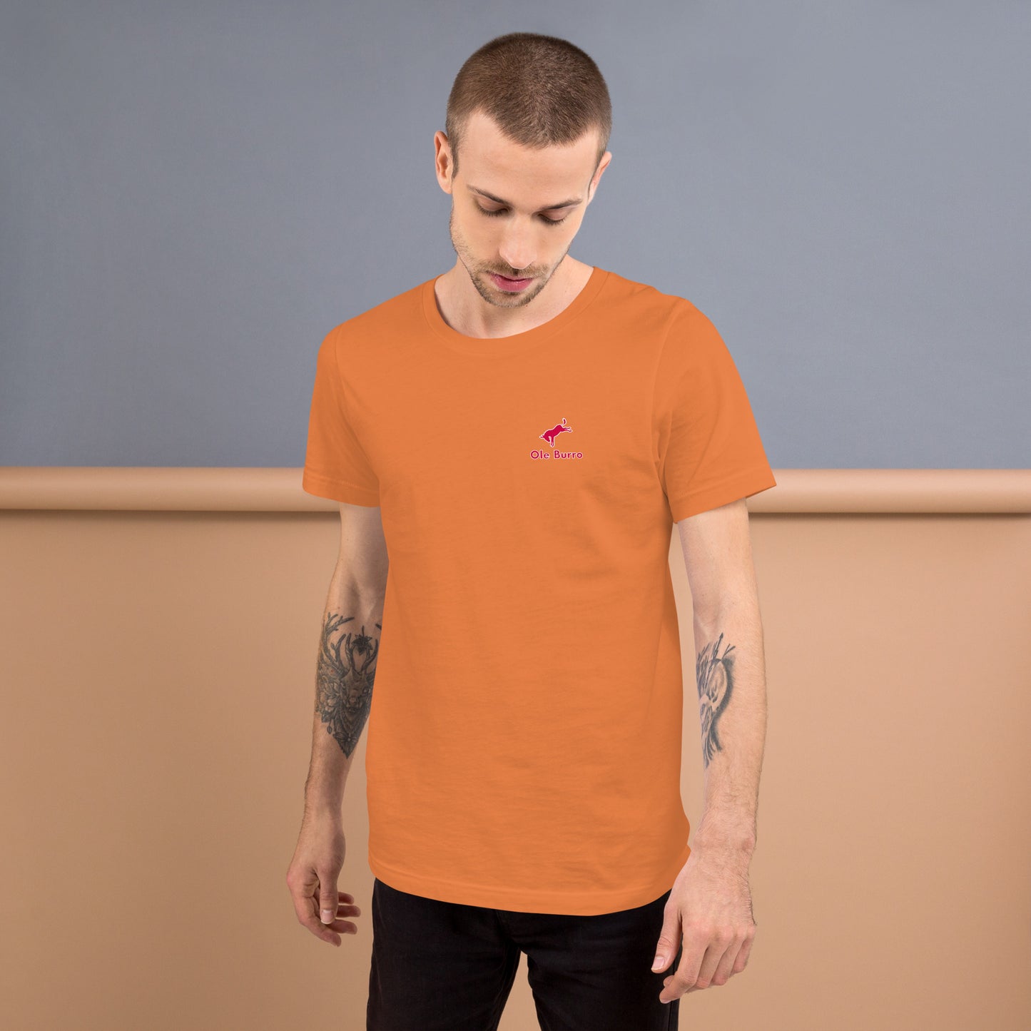 Man wearing an orange t-shirt with a logo on a plain background