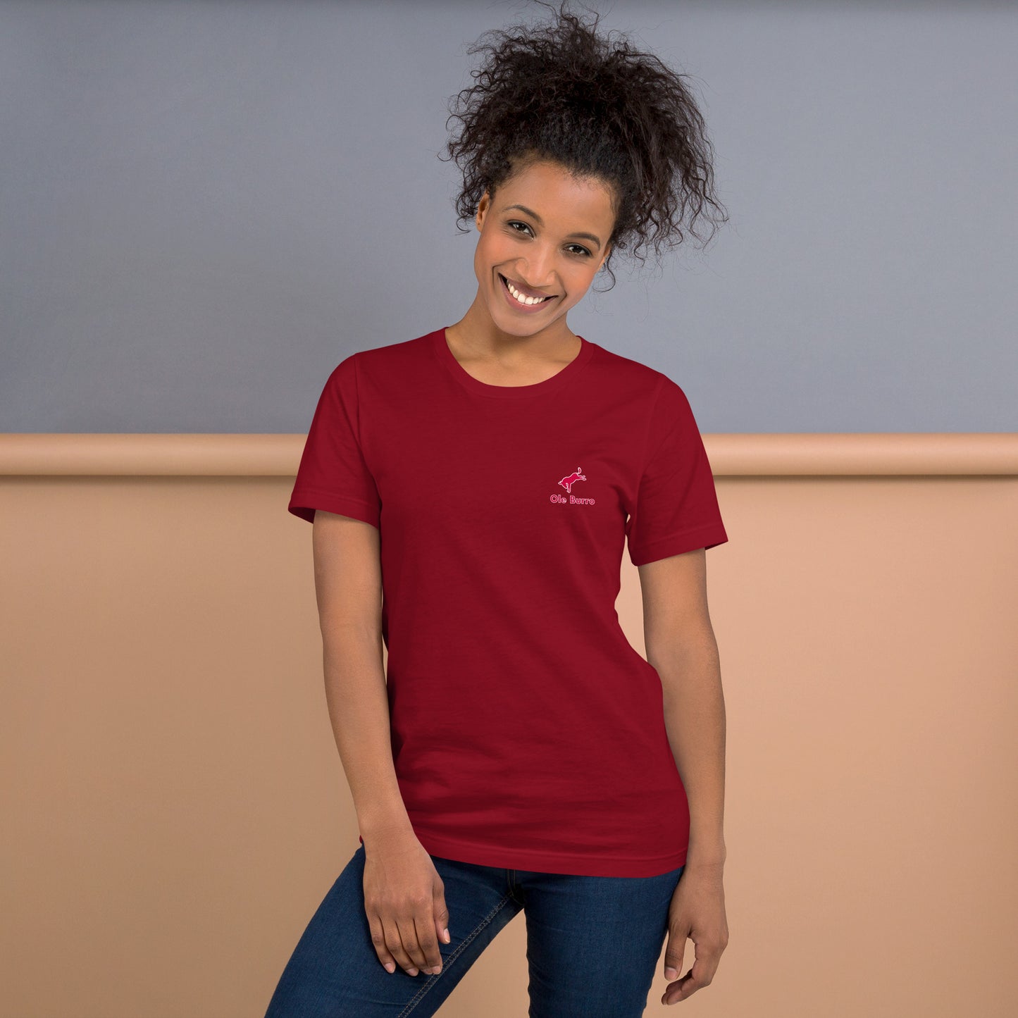 Woman wearing a red t-shirt with a logo against a neutral background