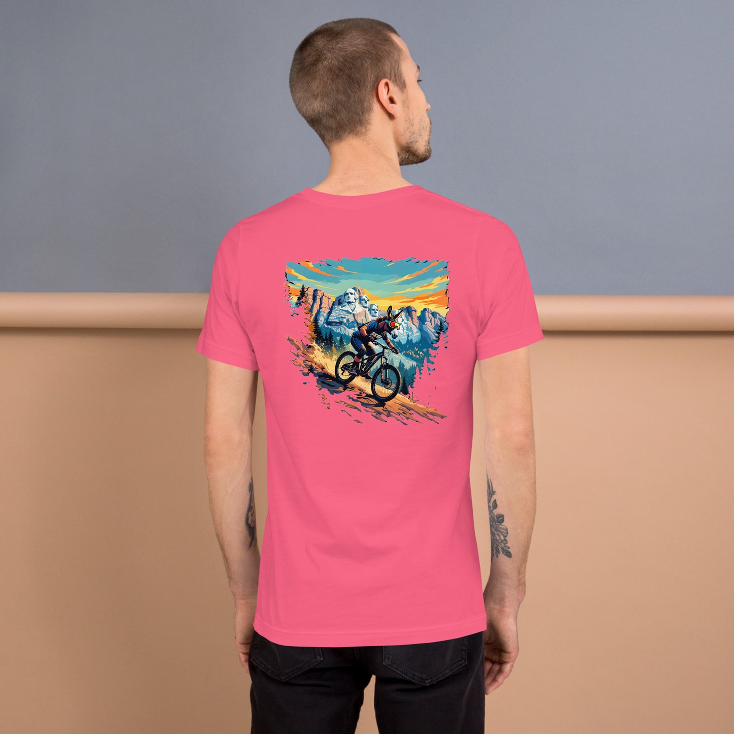 Person wearing a pink t-shirt with a mountain bike graphic on the back, standing against a gradient background.