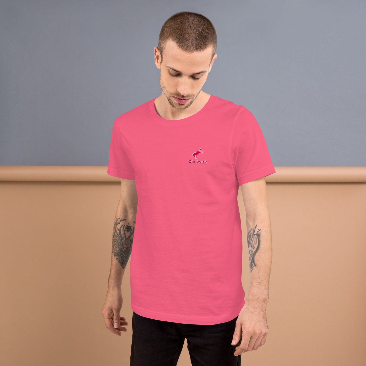 Man wearing a pink t-shirt with a logo against a plain background