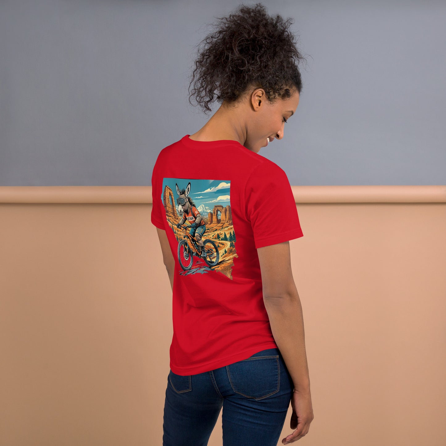 Person wearing a red t-shirt with a colorful graphic on the back, standing against a neutral background.